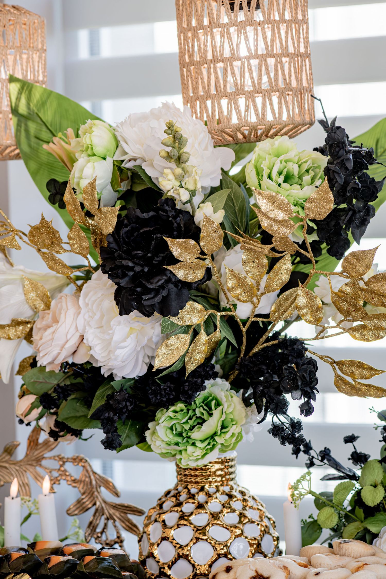 Elegant floral centerpiece with black, white and gold flowers in a decorative gold and white vase.
