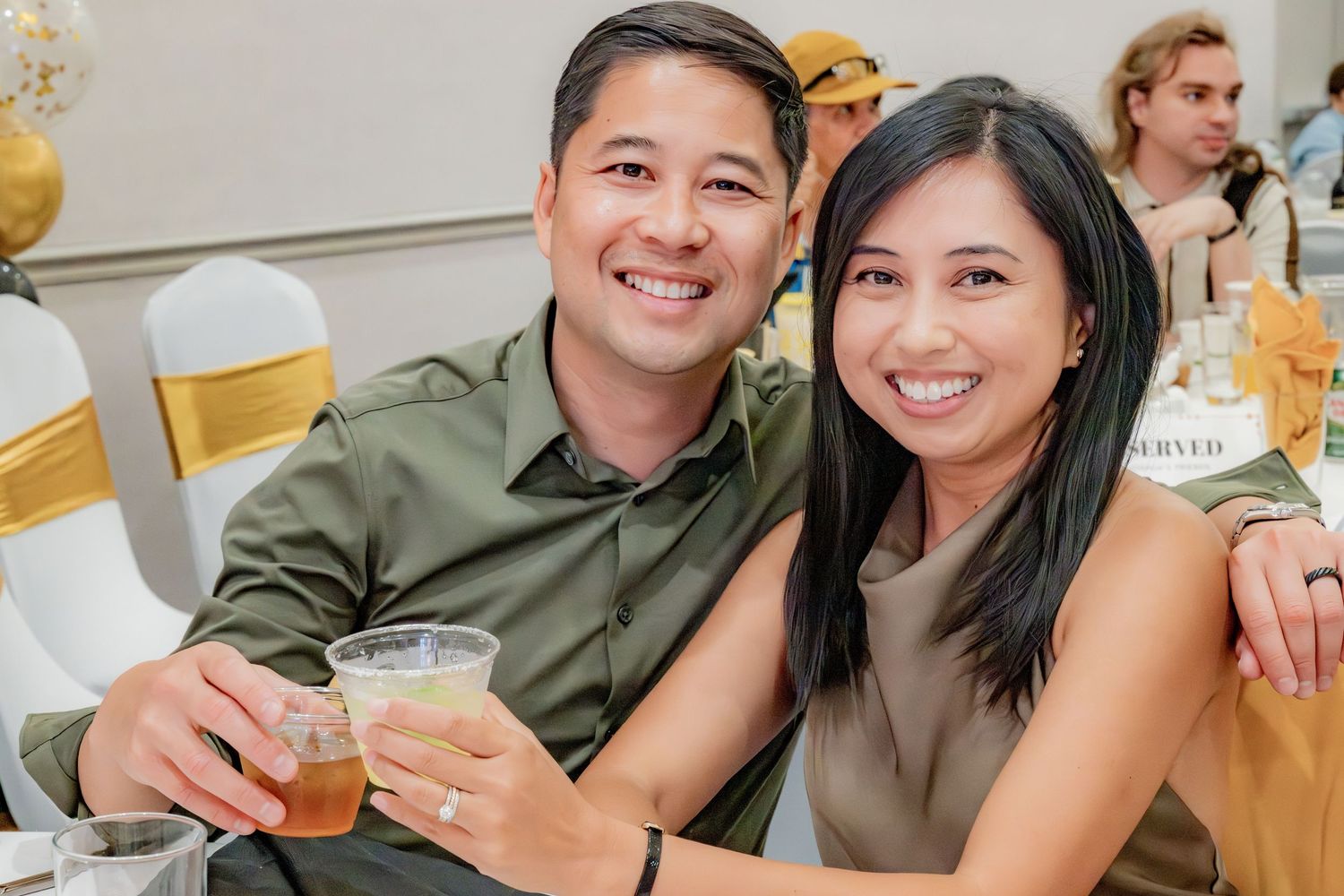 Happy couple holding drinks and smiling together at an elegant birthday party celebration.