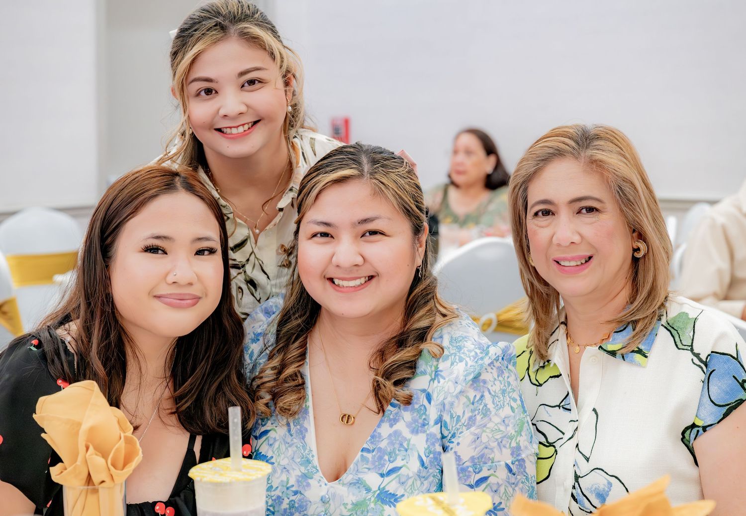 Four smiling women posing together at a festive birthday party with yellow napkin decorations.