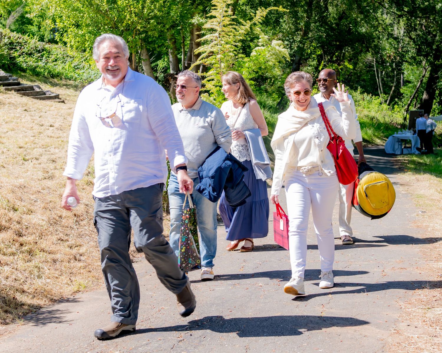 Group of guests walking along a sunny outdoor path to an event.