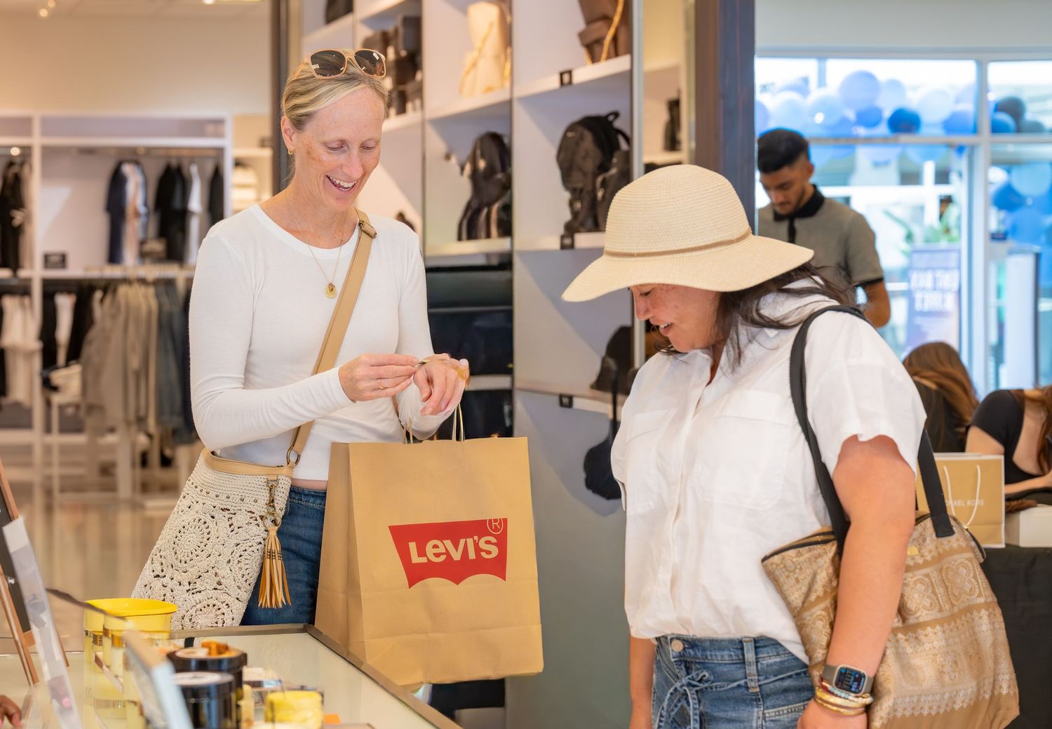 Two women shopping at a Levis store, looking at items in a bag.