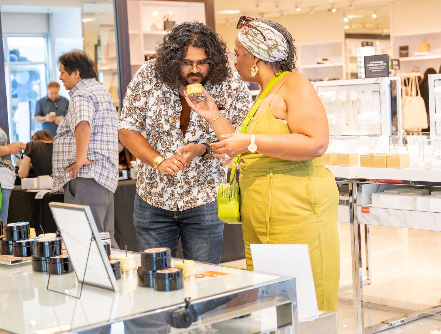 Two people conversing and smiling near a glass display case in a beauty store.