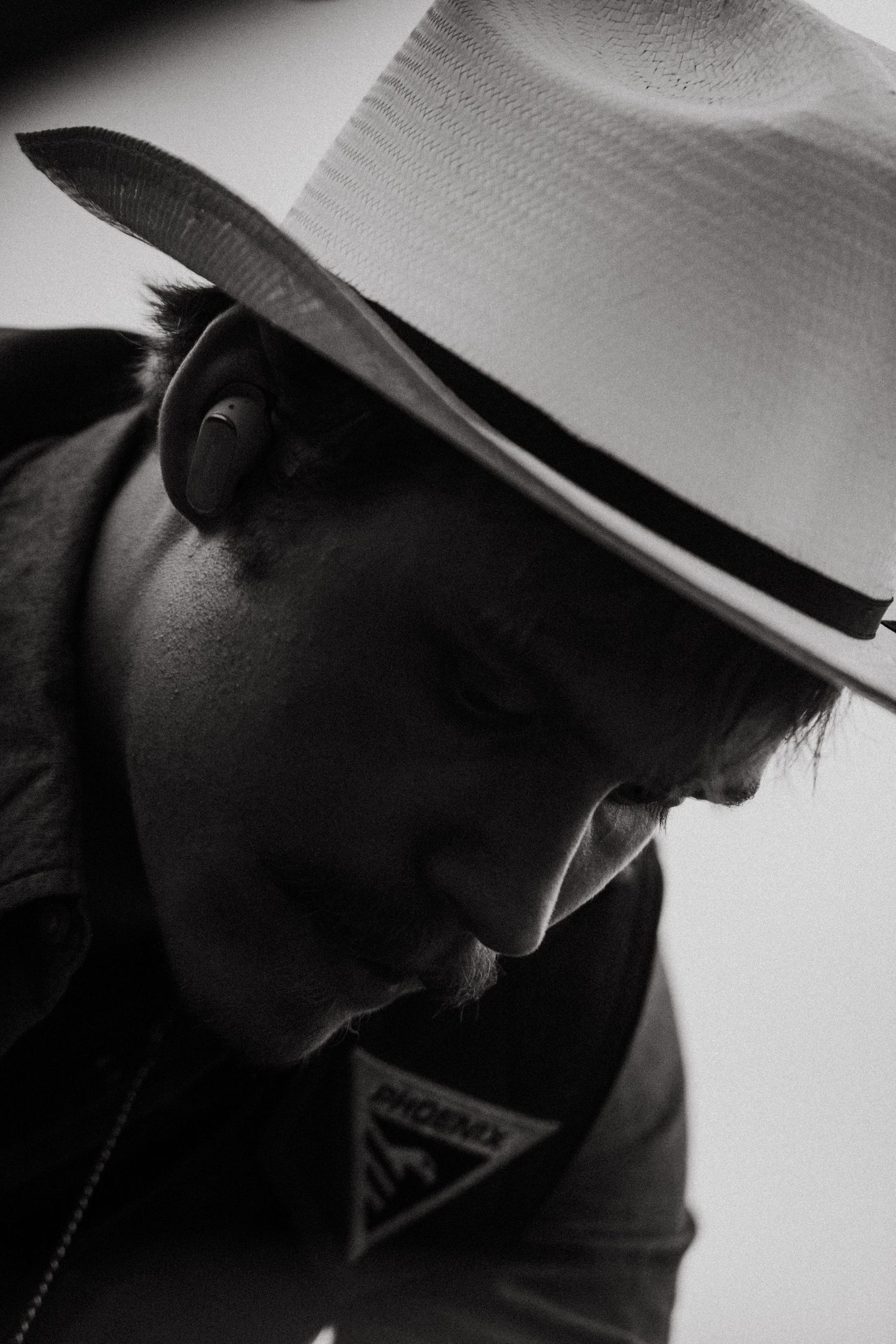 Black and white portrait of a man wearing a white fedora hat looking down.