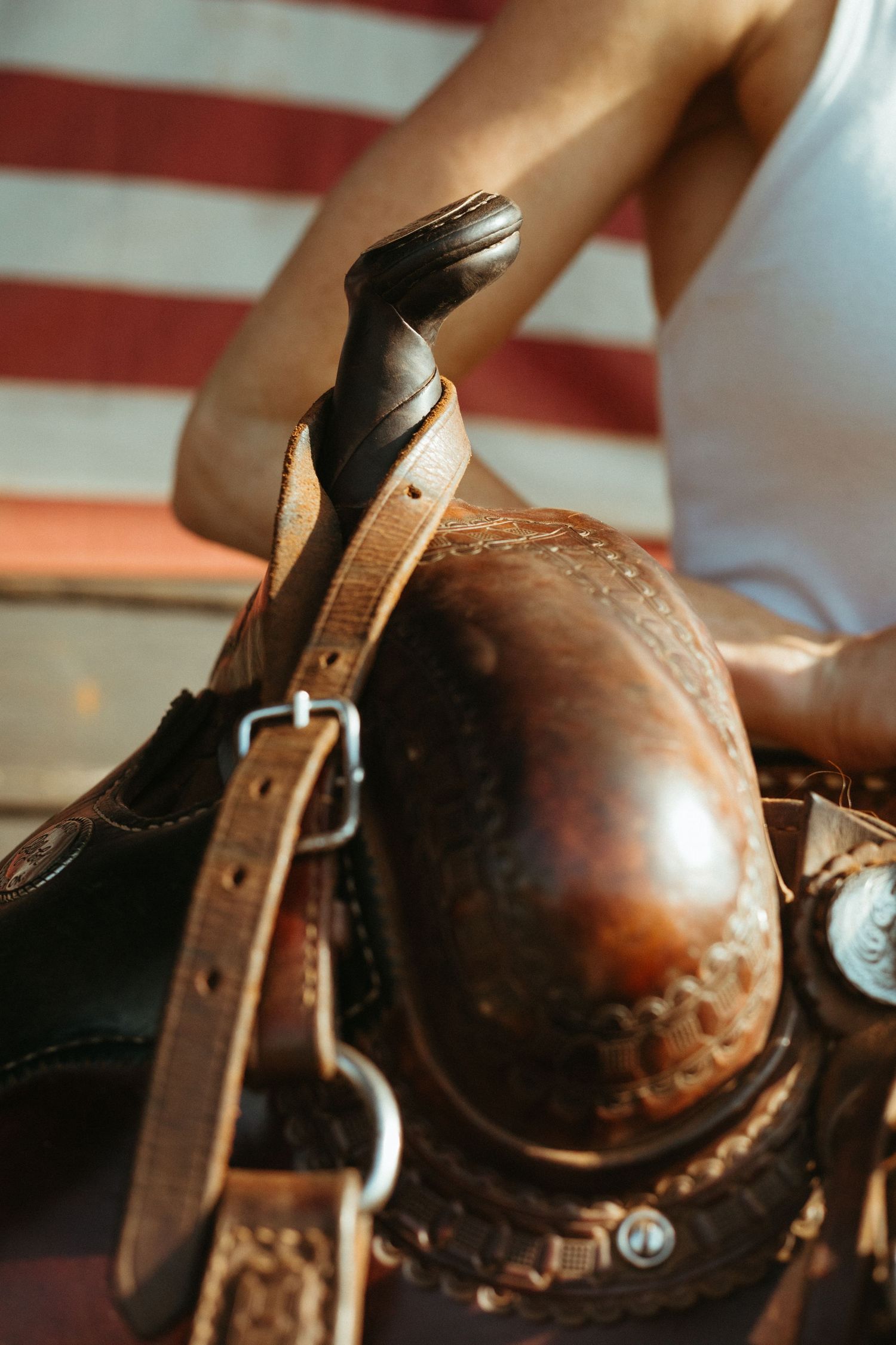 Close-up of a ornate brown leather western saddle with American flag background.