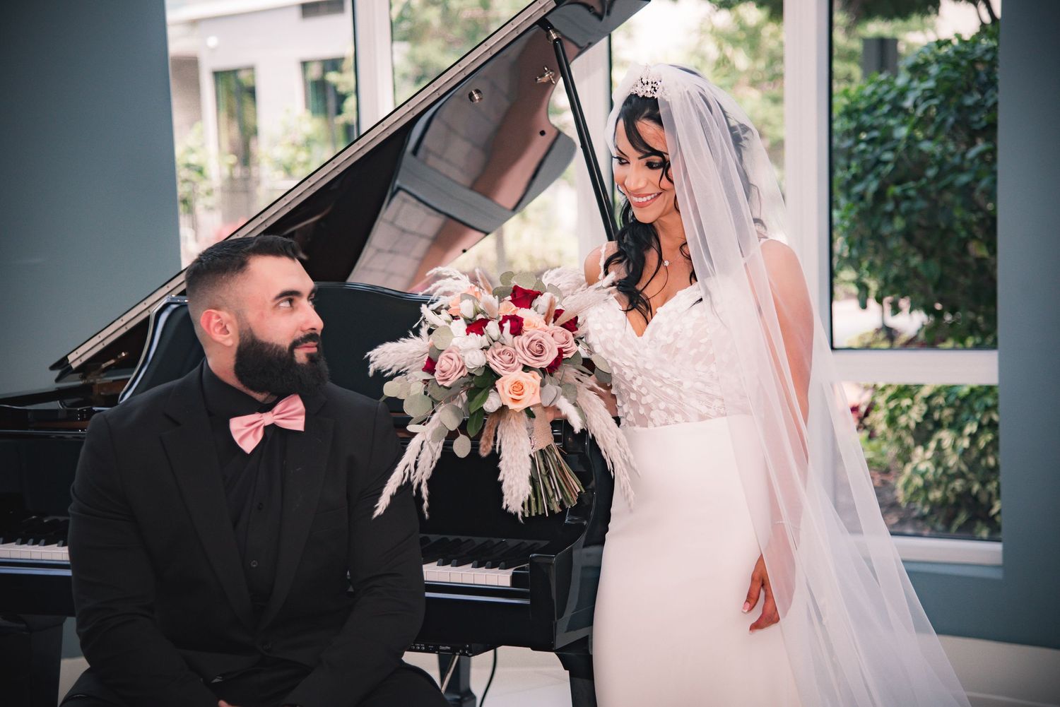 Elegant wedding ceremony setup with white chairs and floral arrangements near large windows.