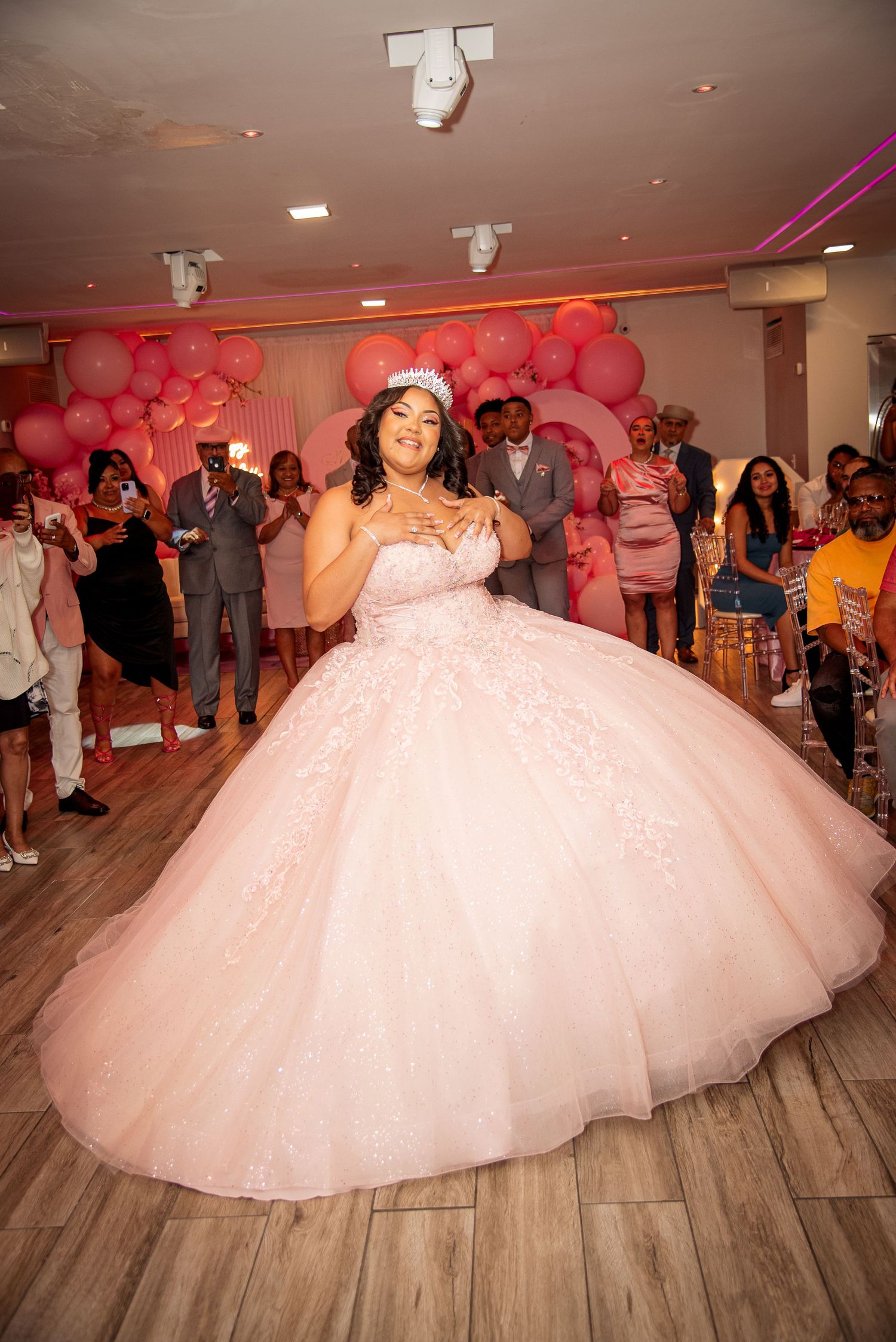 Young woman in a voluminous blush pink ball gown and tiara dancing at a quinceañera celebration by FBM Studios in Fort Lauderdale Florida.