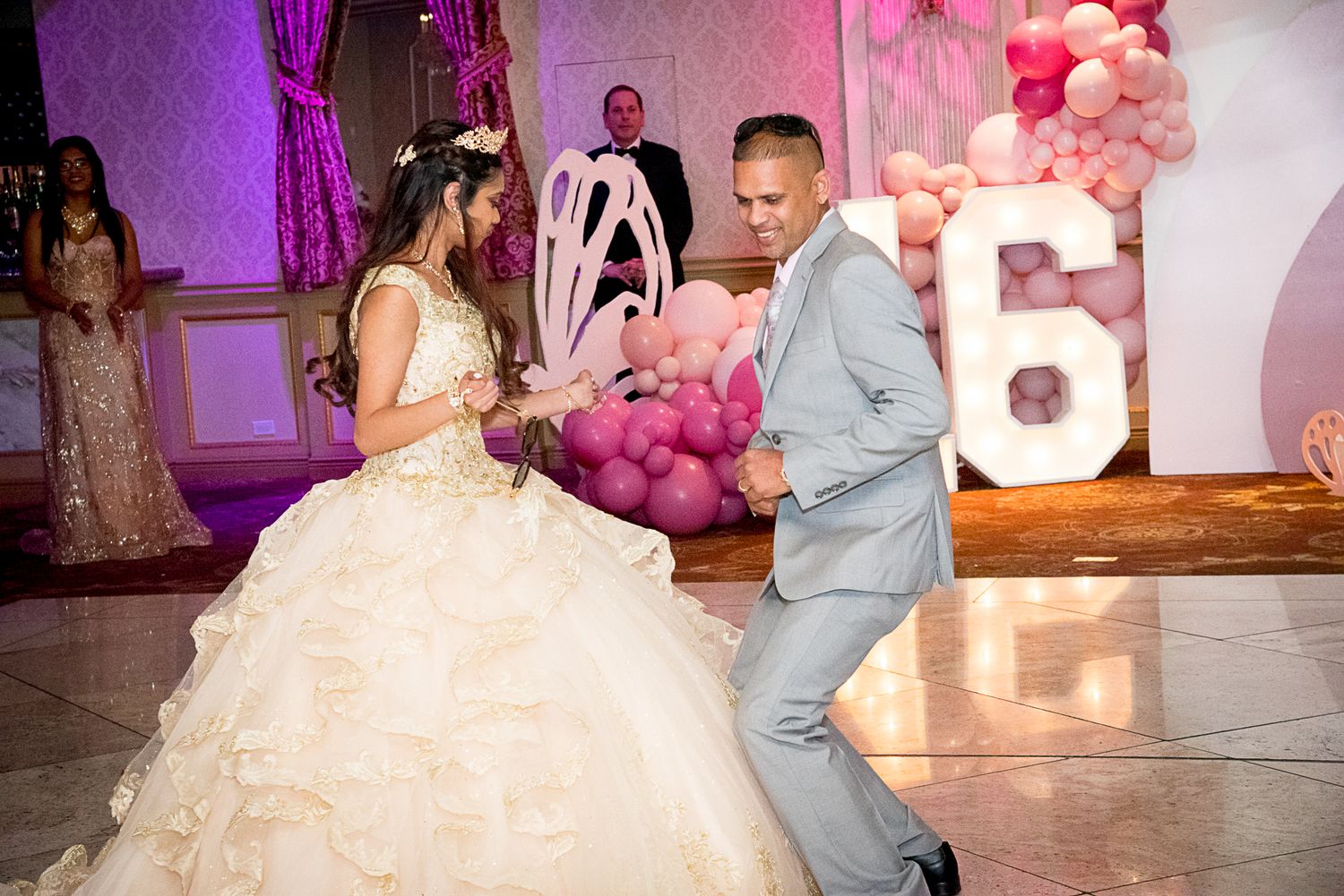 A young woman in a white quinceañera ball gown dances with a man in a gray suit at a pink-themed celebration by FBM Studios in Fort Lauderda