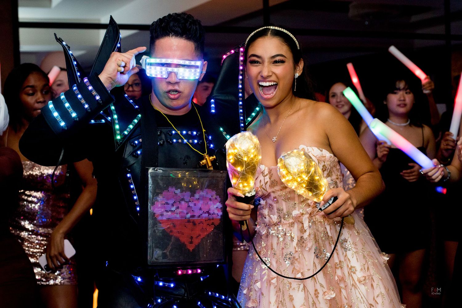 Two party guests pose with LED light-up glasses and glowing decorations at a festive celebration event by FBM Studios in Fort Lauderdale Fl