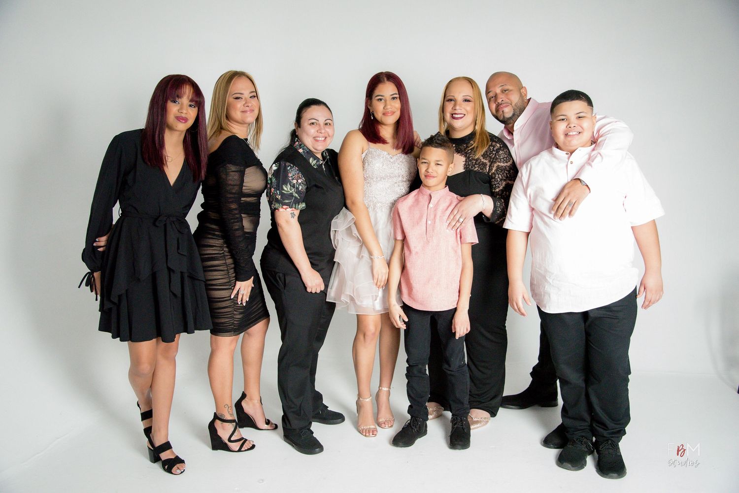A joyful family group of eight posing together in a professional photo studio by FBM Studios in Fort Lauderdale Fl