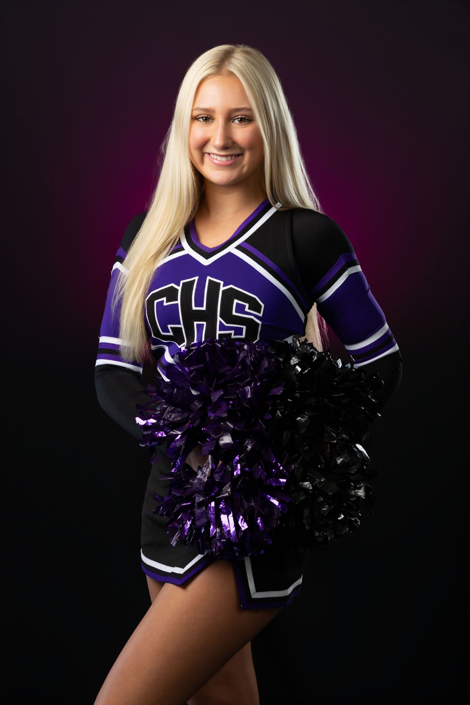 Blonde cheerleader in purple CHS uniform holding pom-poms against a dark background.