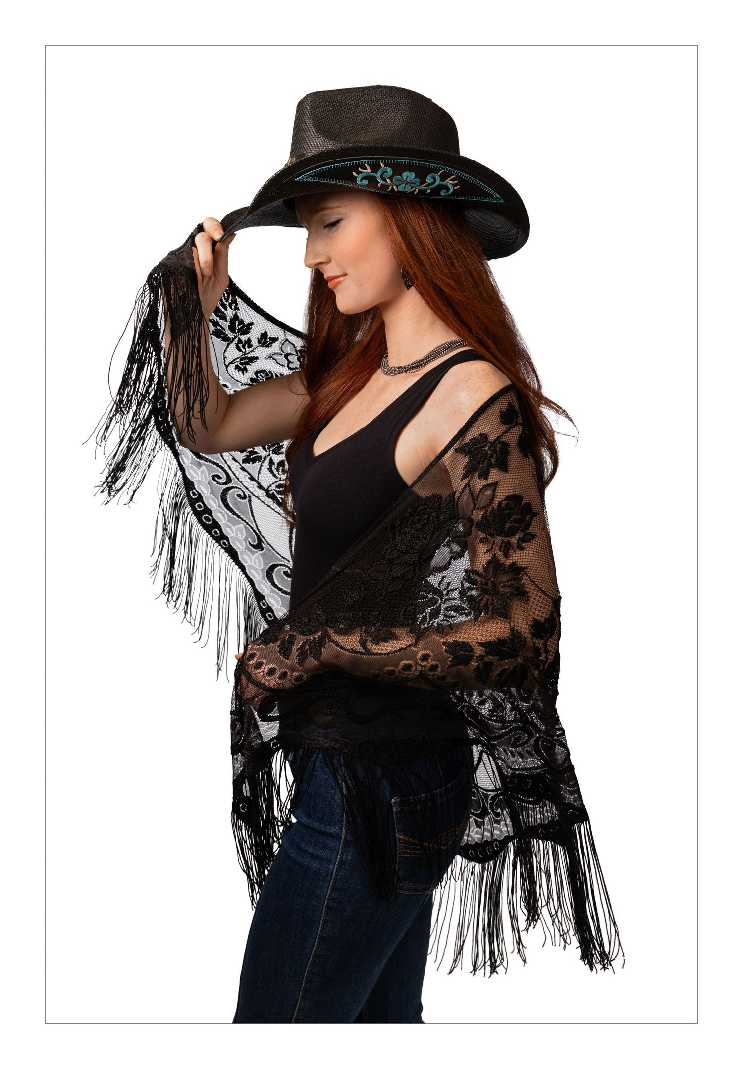 Woman in black lace shawl with fringe, black tank top, jeans, and black cowboy hat with turquoise trim.