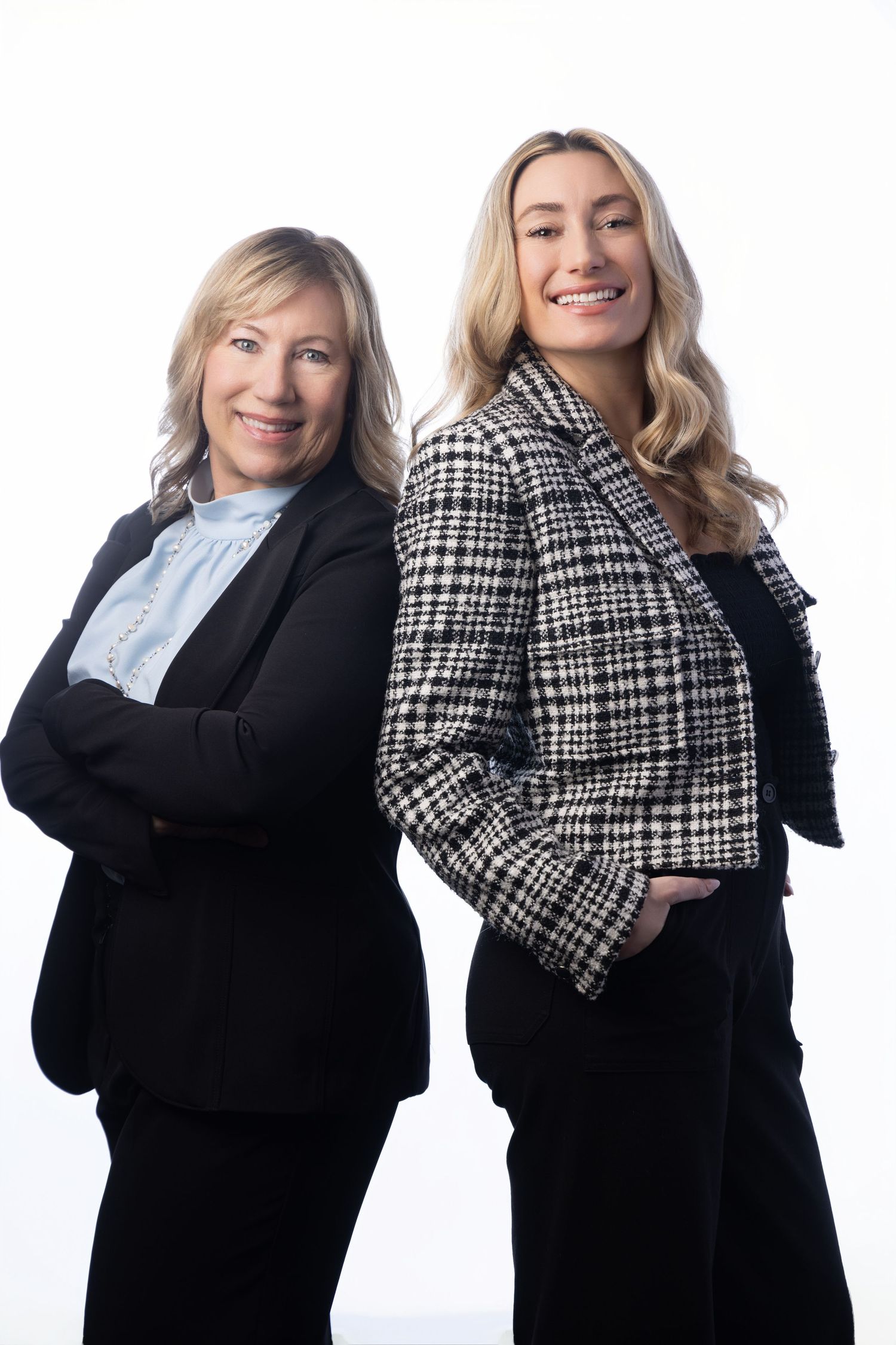 Two professional women in business attire smiling confidently against a white background.