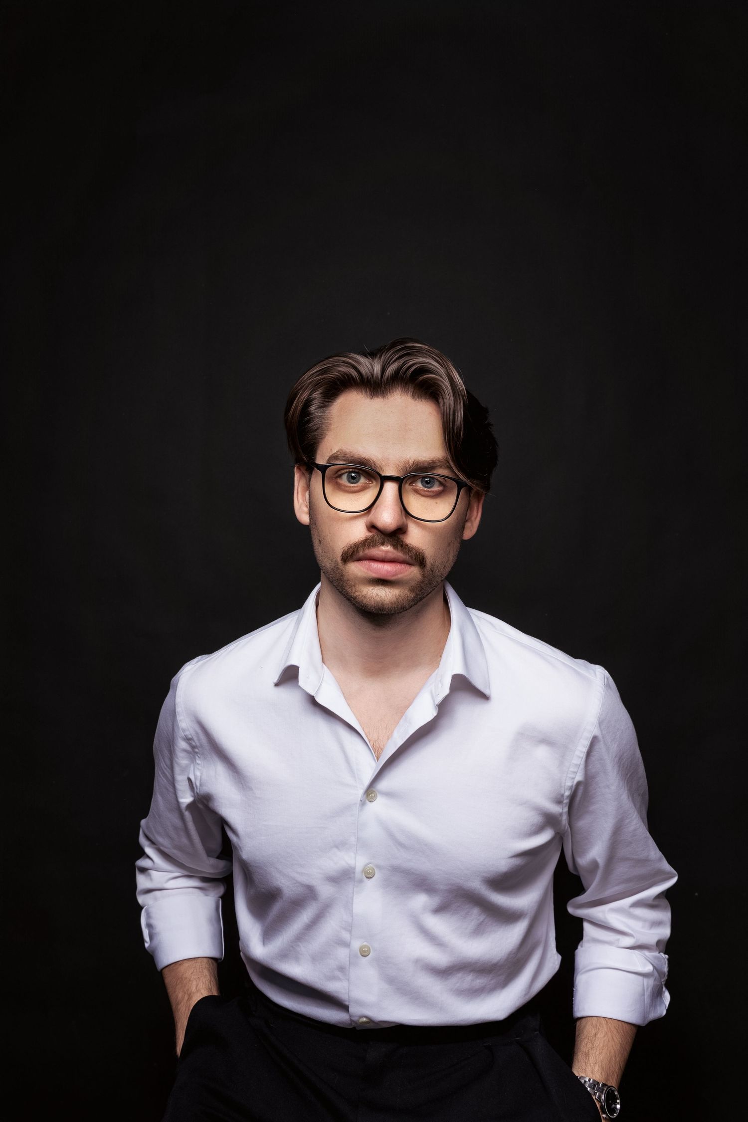 Portret mężczyzny w studio na czarnym tle, elegancka stylizacja i mocny kontrast