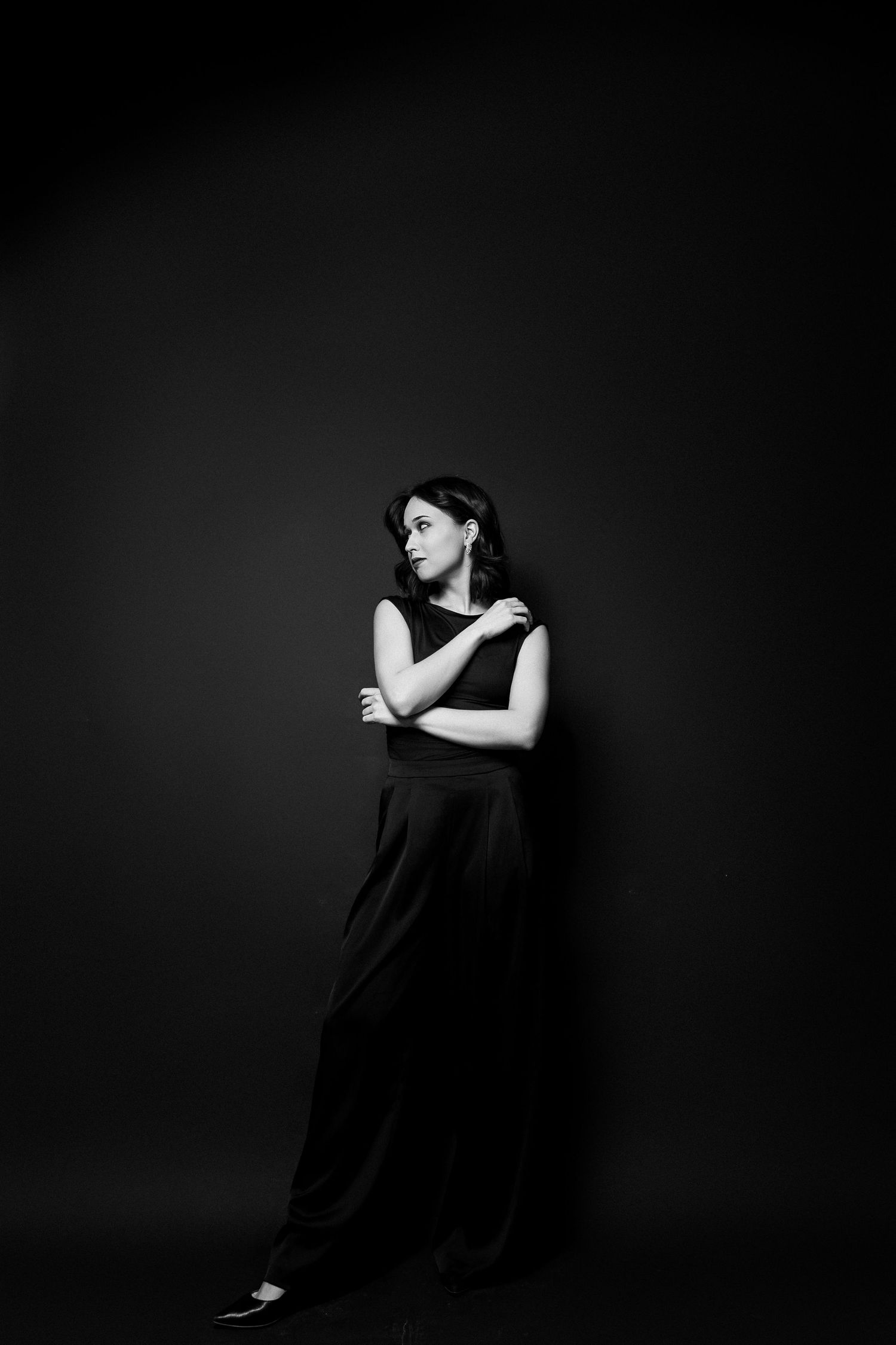 Pełna sylwetka kobiety w studio na czarnym tle, elegancka poza