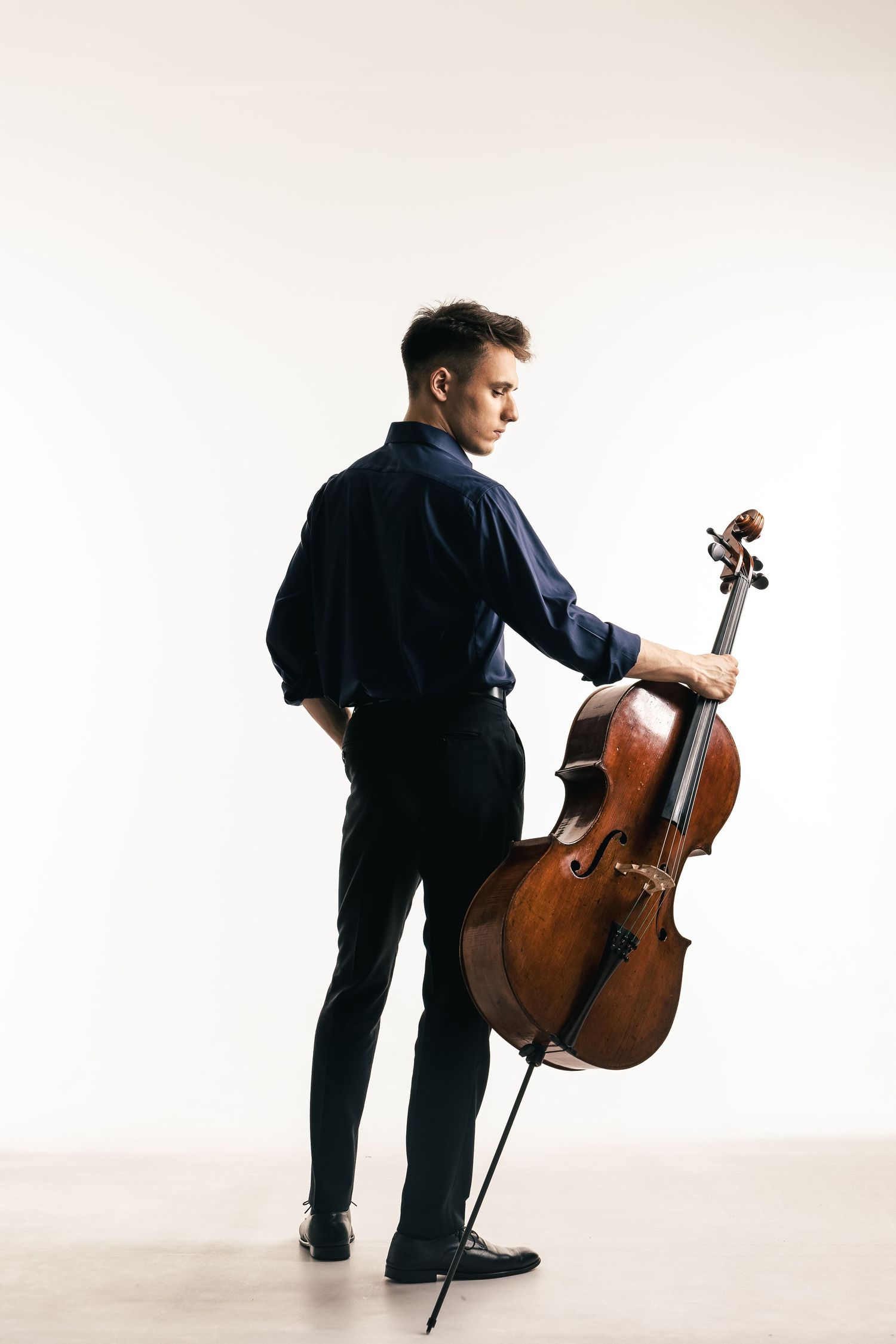 Pełna sylwetka muzyka z instrumentem smyczkowym w studio, jasne tło