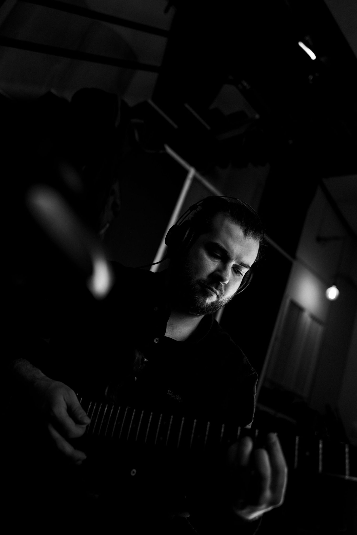 Czarno-białe portretowe ujęcie muzyka w trakcie nagrania, studio nagraniowe