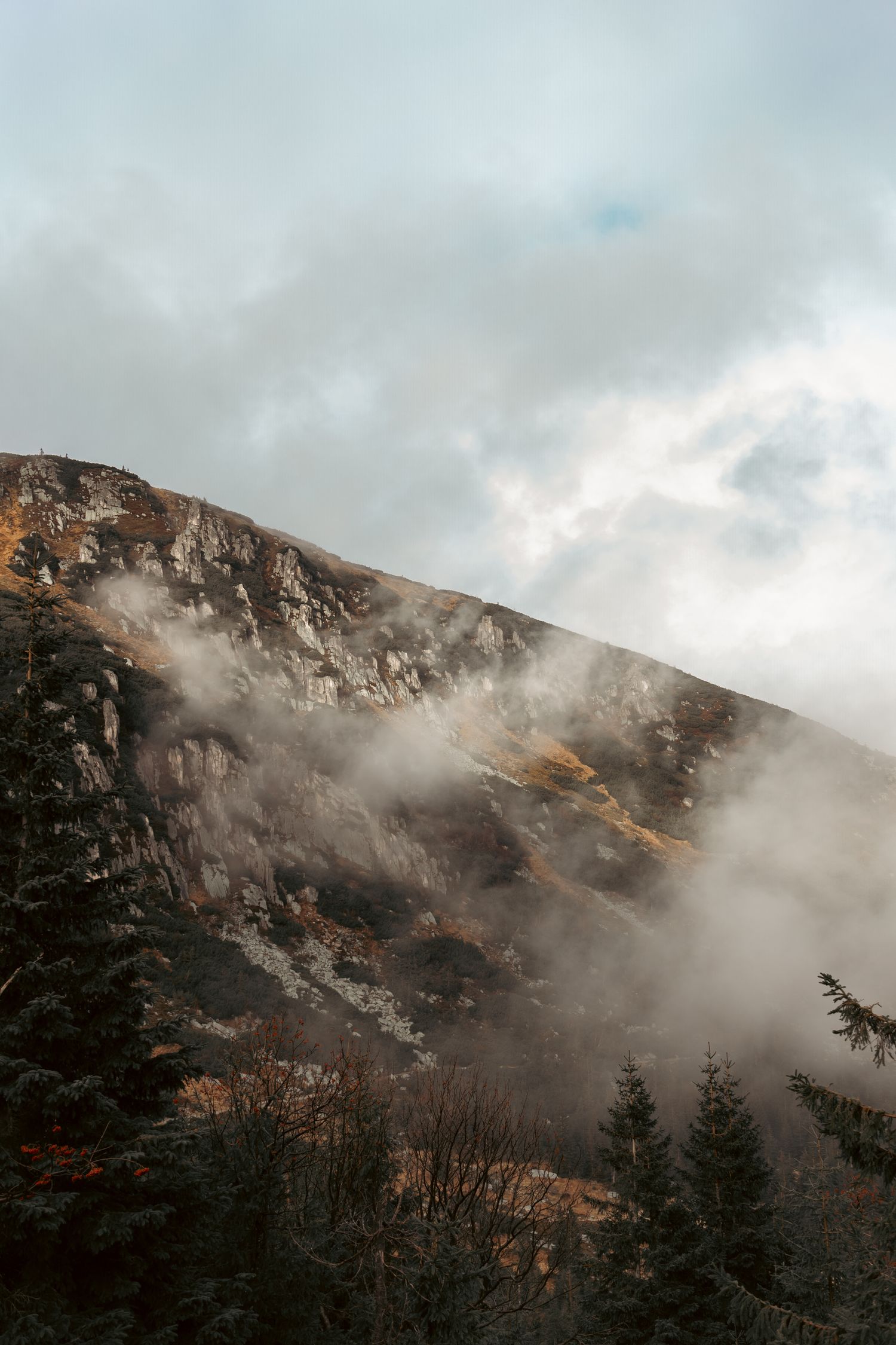 Górski krajobraz z chmurami i mgłą nad zboczami, fotografia natury; karkonosze