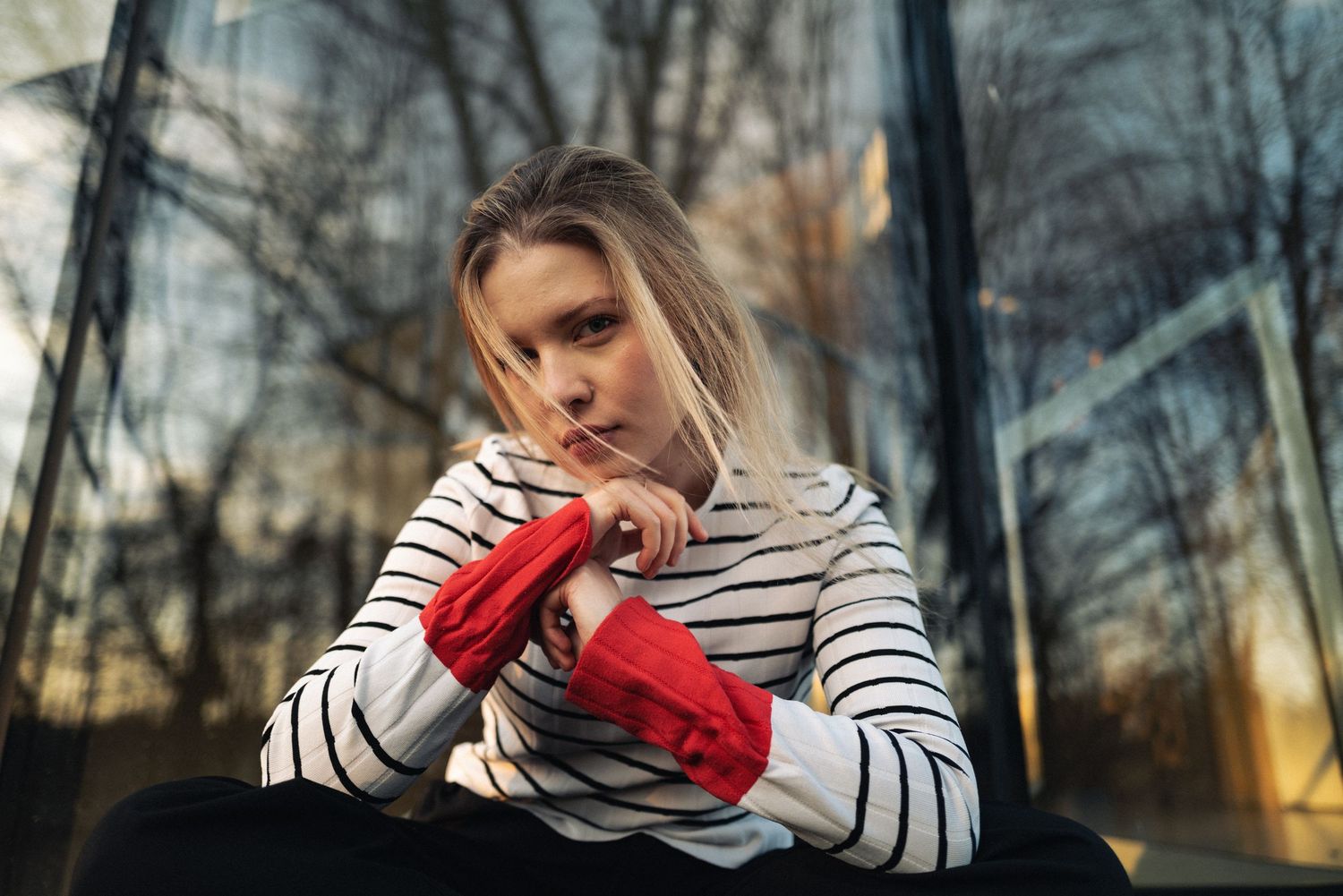 Portret kobiety w plenerze, czerwone rękawiczki i tło lasu o zachodzie słońca