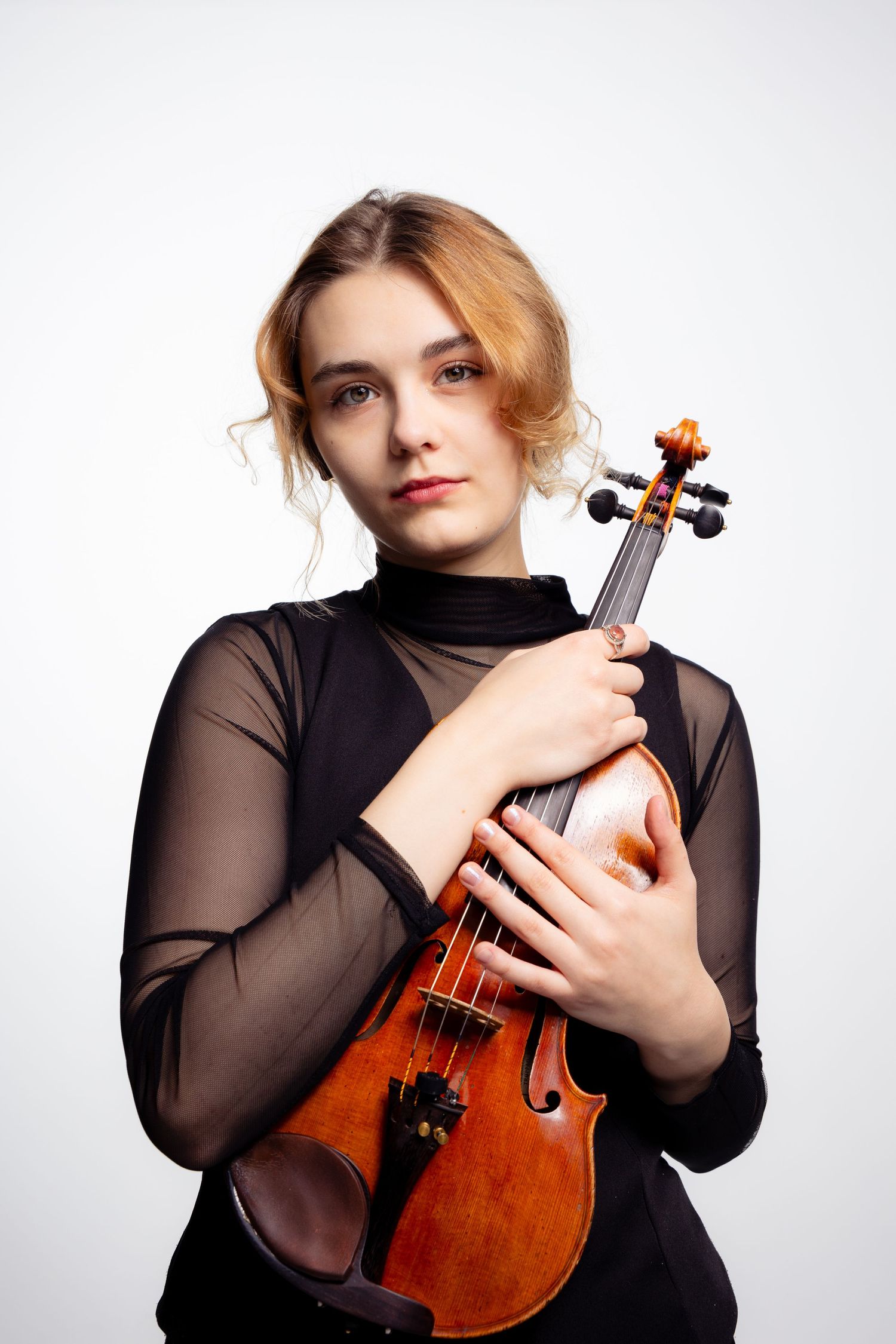 Portret skrzypaczki w studio na jasnym tle, instrument trzymany blisko ciała