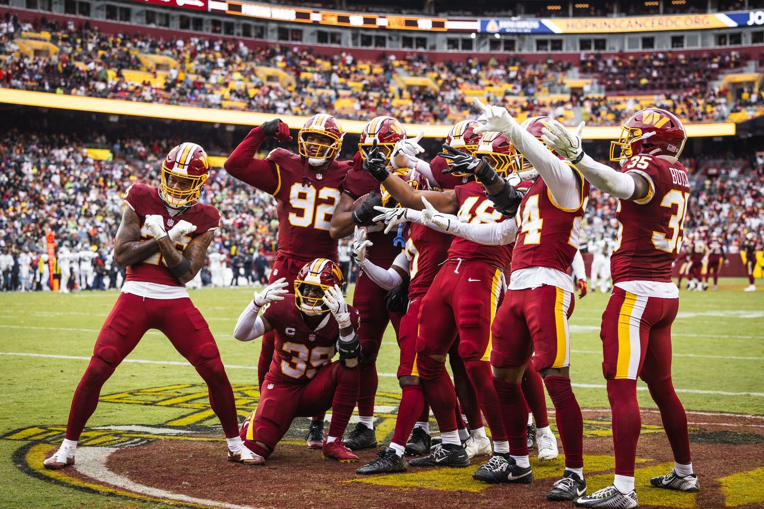 Washington Commanders NFL players celebrate a touchdown in a group huddle at FedExField during a home game.