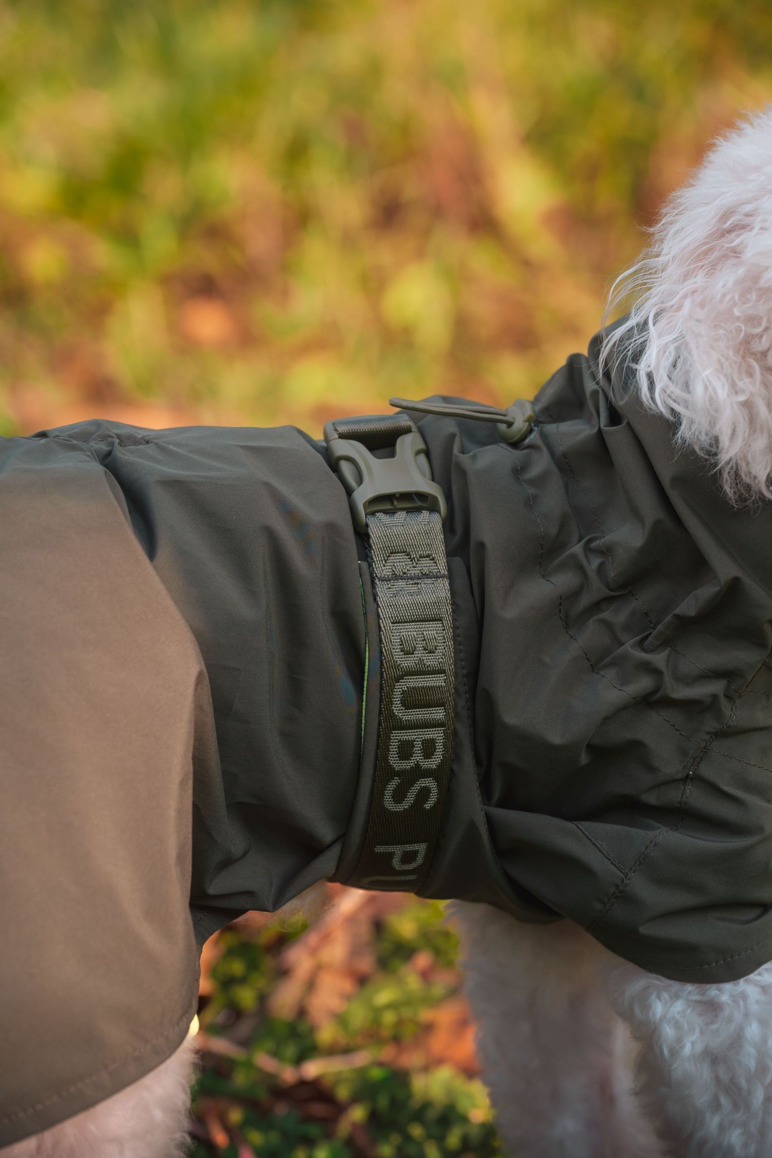 Close-up view of a black rain jacket sleeve with a gray embroidered patch detail.