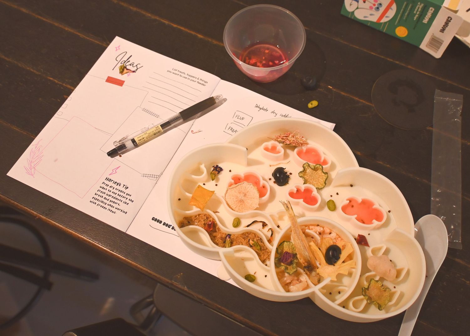Plates of food and drinks arranged on a dark wooden table in a restaurant setting.