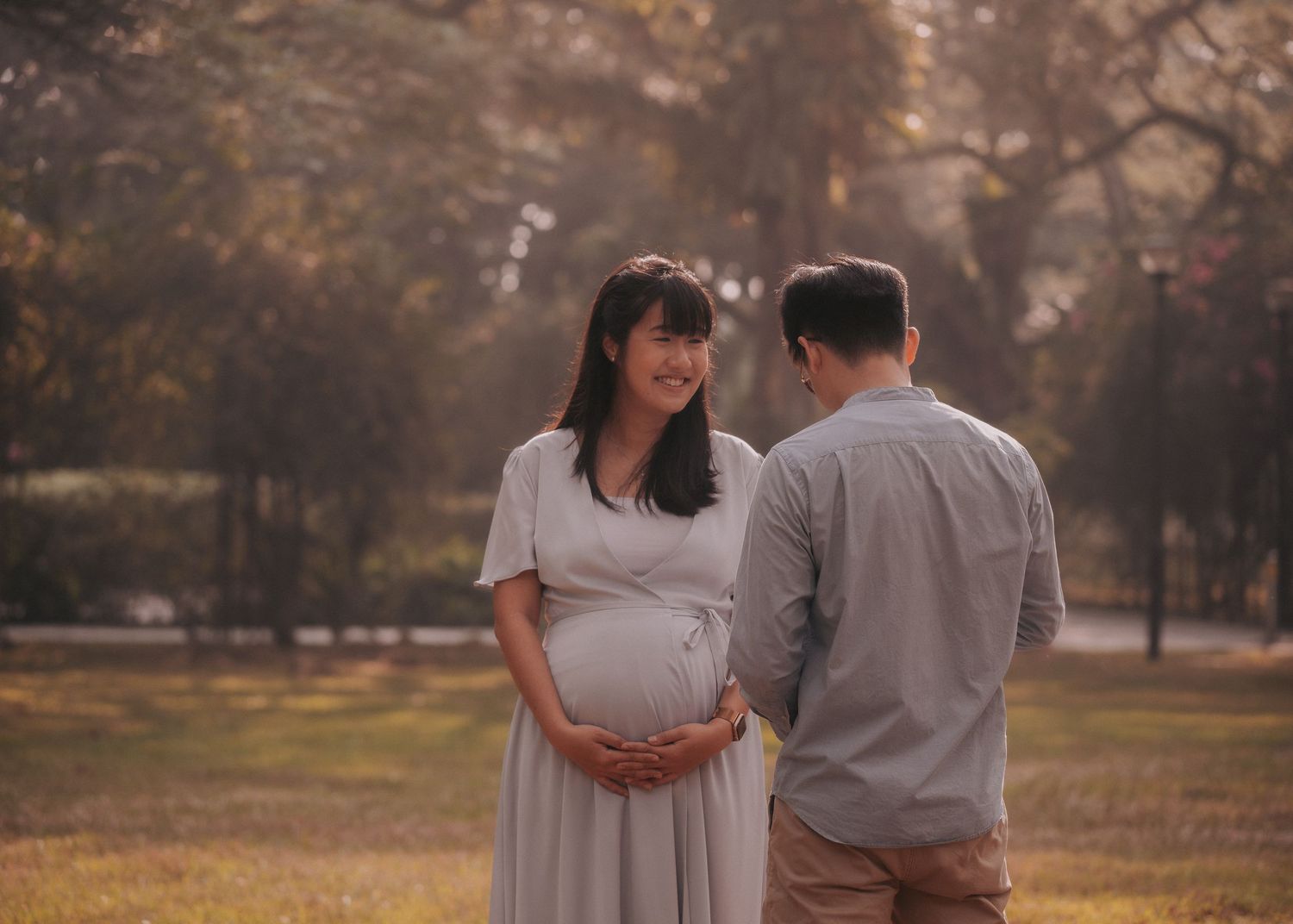 A couple shares an intimate moment in a park during golden hour.