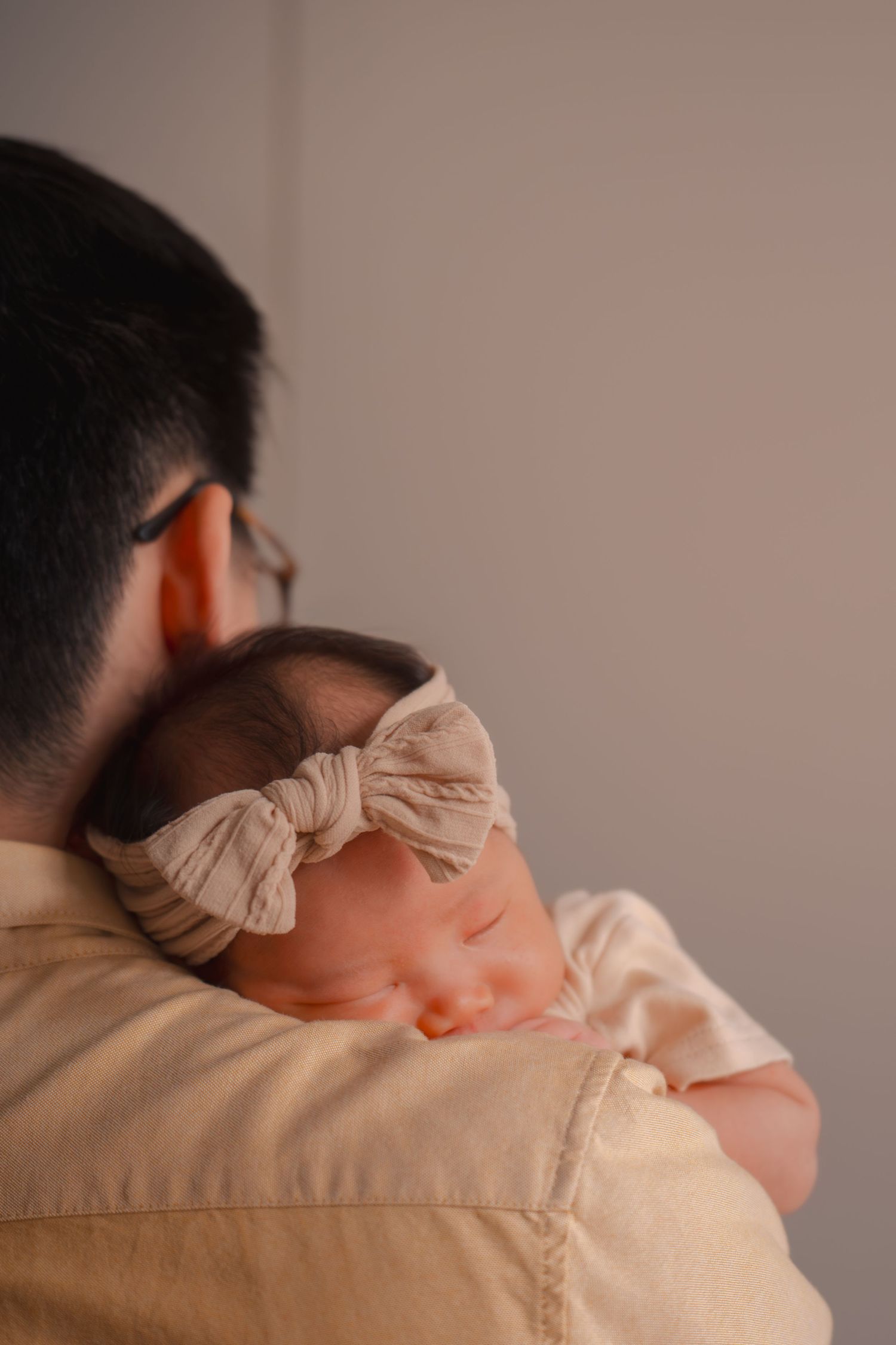 Parent holding sleeping infant close to shoulder in peaceful moment.