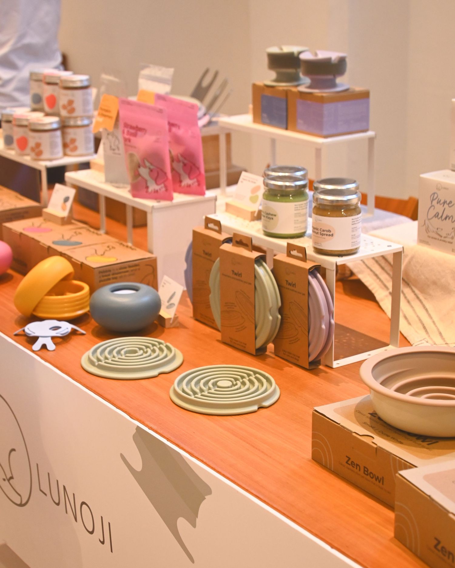 Lunoji brand display table featuring zen bowls, coasters, candles, and eco-friendly packaged products at a retail showcase.
