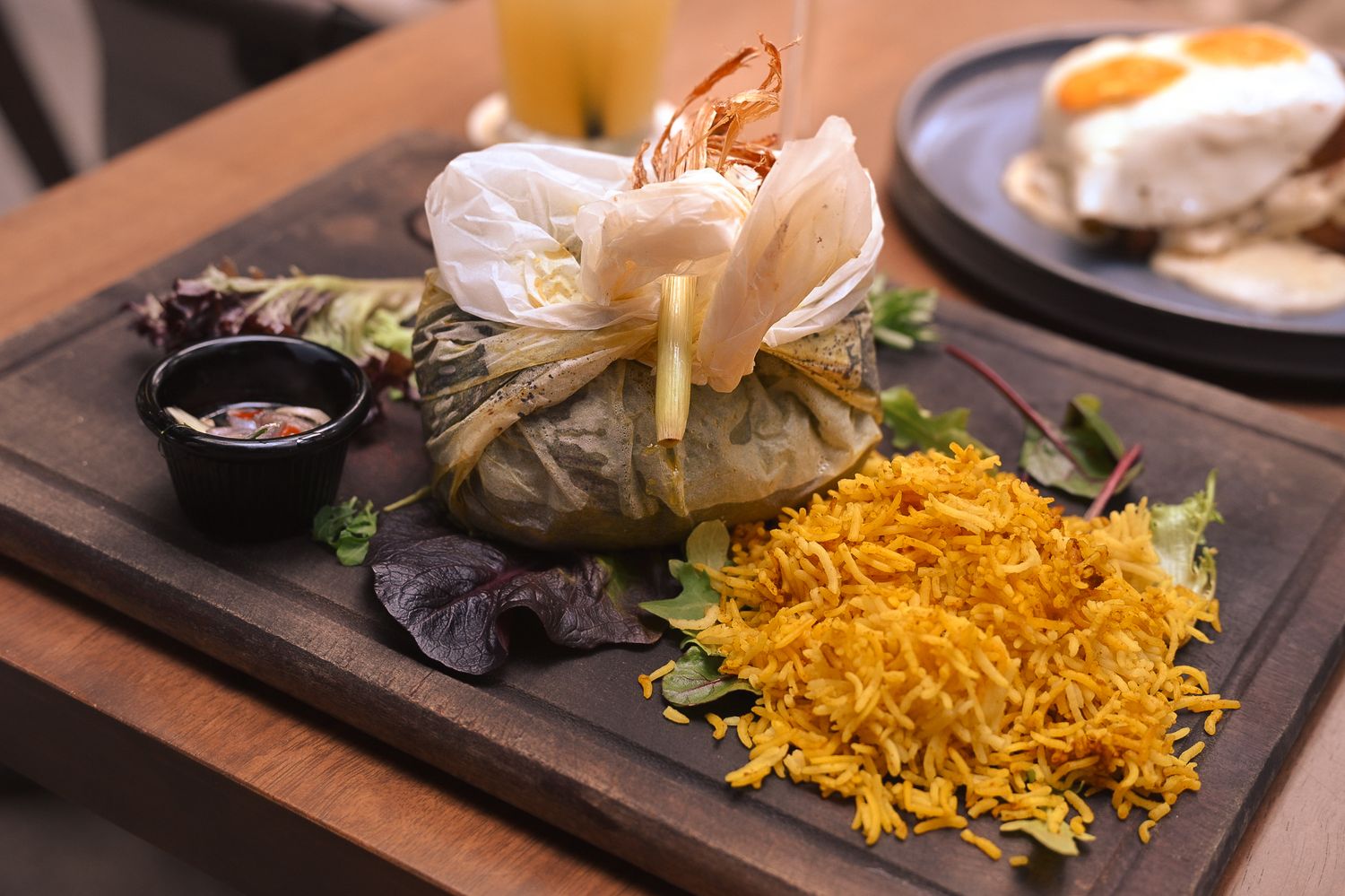 Close-up of yellow rice and fried dishes served on wooden table.