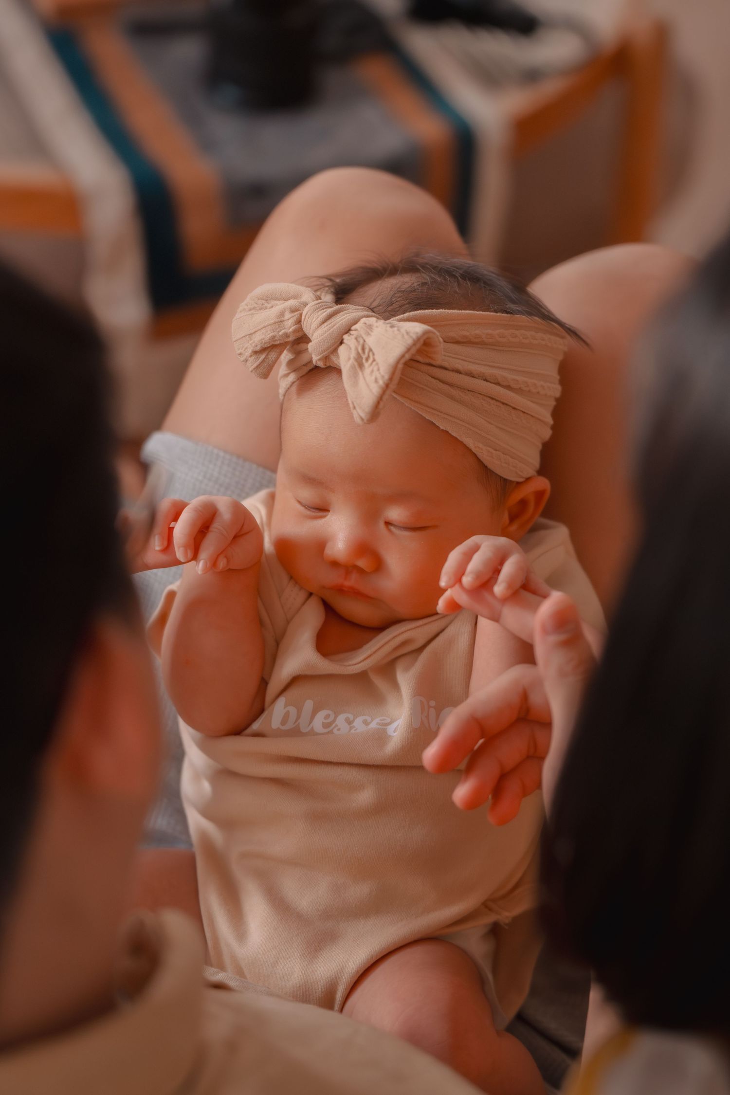 Sleeping baby in cream outfit with bow headband resting peacefully.