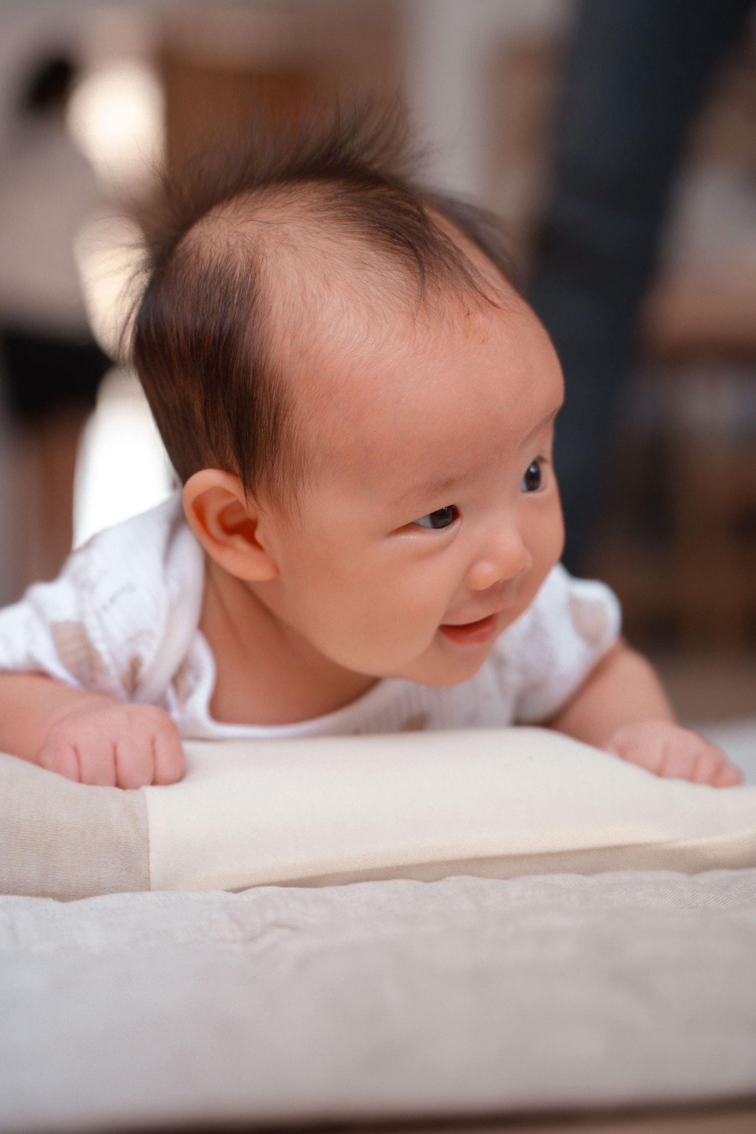 A series of photos showing a baby lying on a white surface, turning their head and gazing to the side.