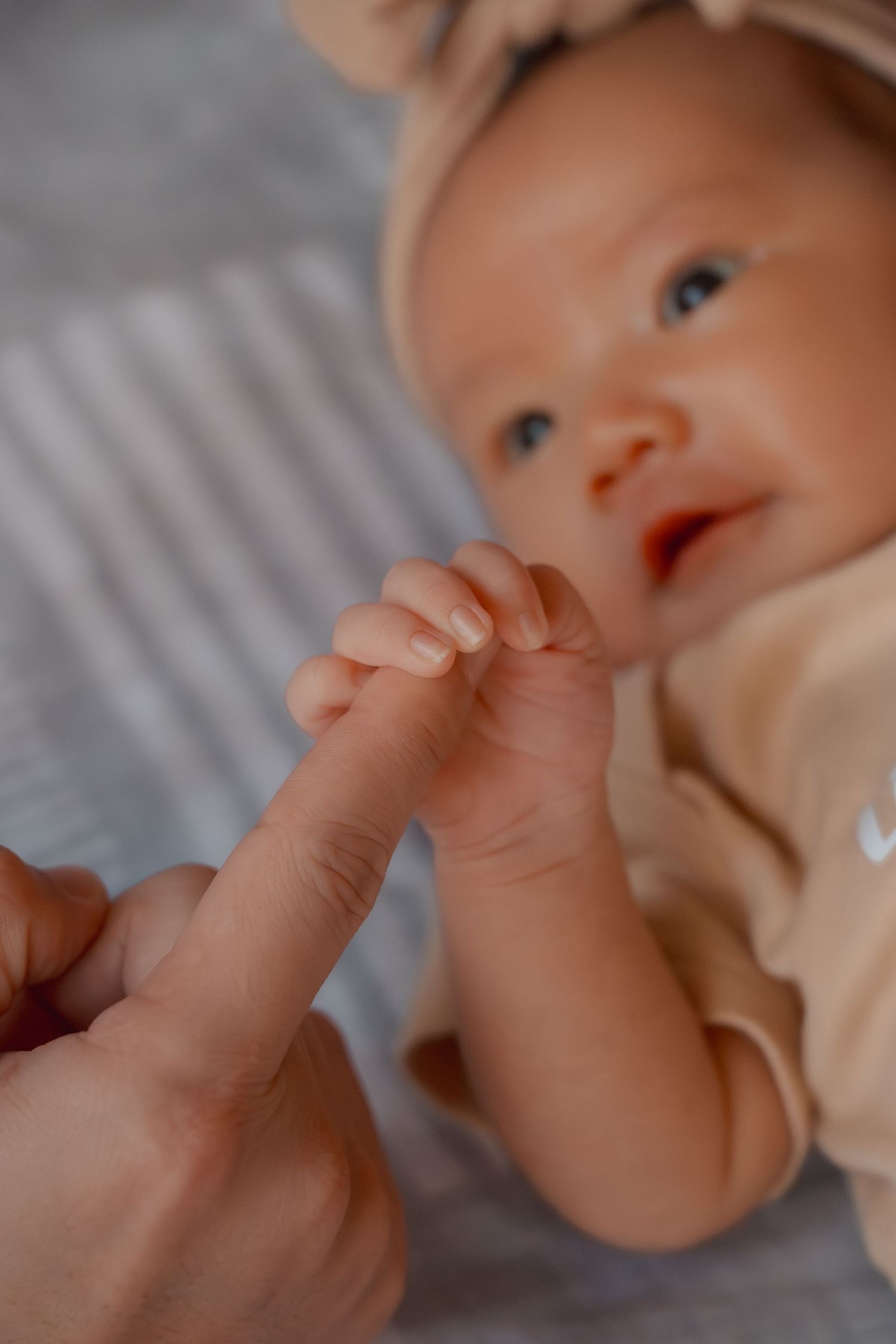 Baby's tiny hand reaching up against a blurred background.