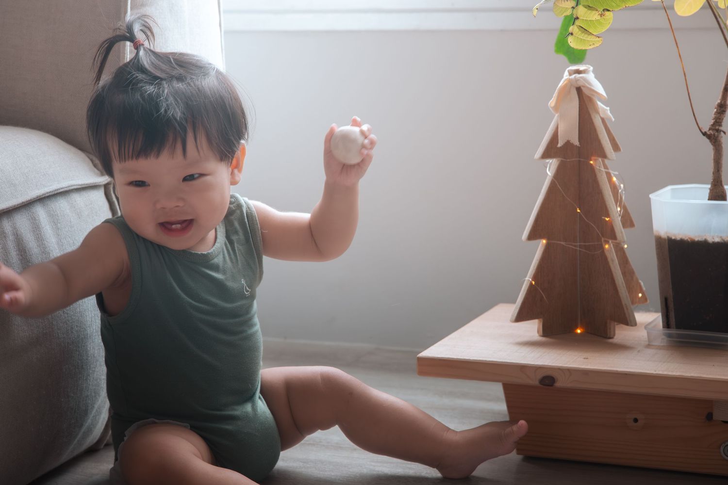 Child excitedly decorates a brown gingerbread Christmas tree cookie with white icing during holiday baking activity.