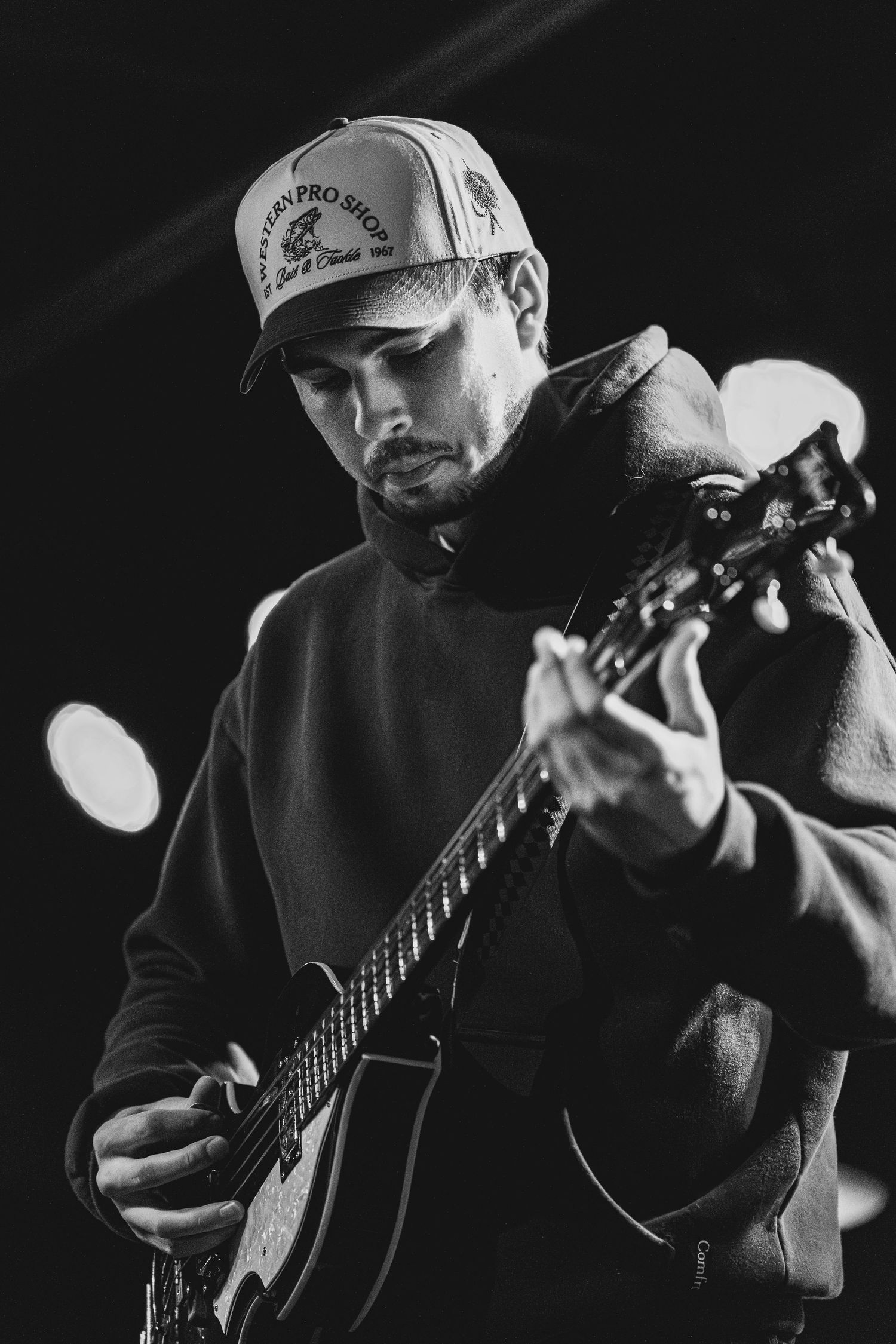 A series of black and white photos showing a musician performing with an acoustic guitar in dramatic lighting.