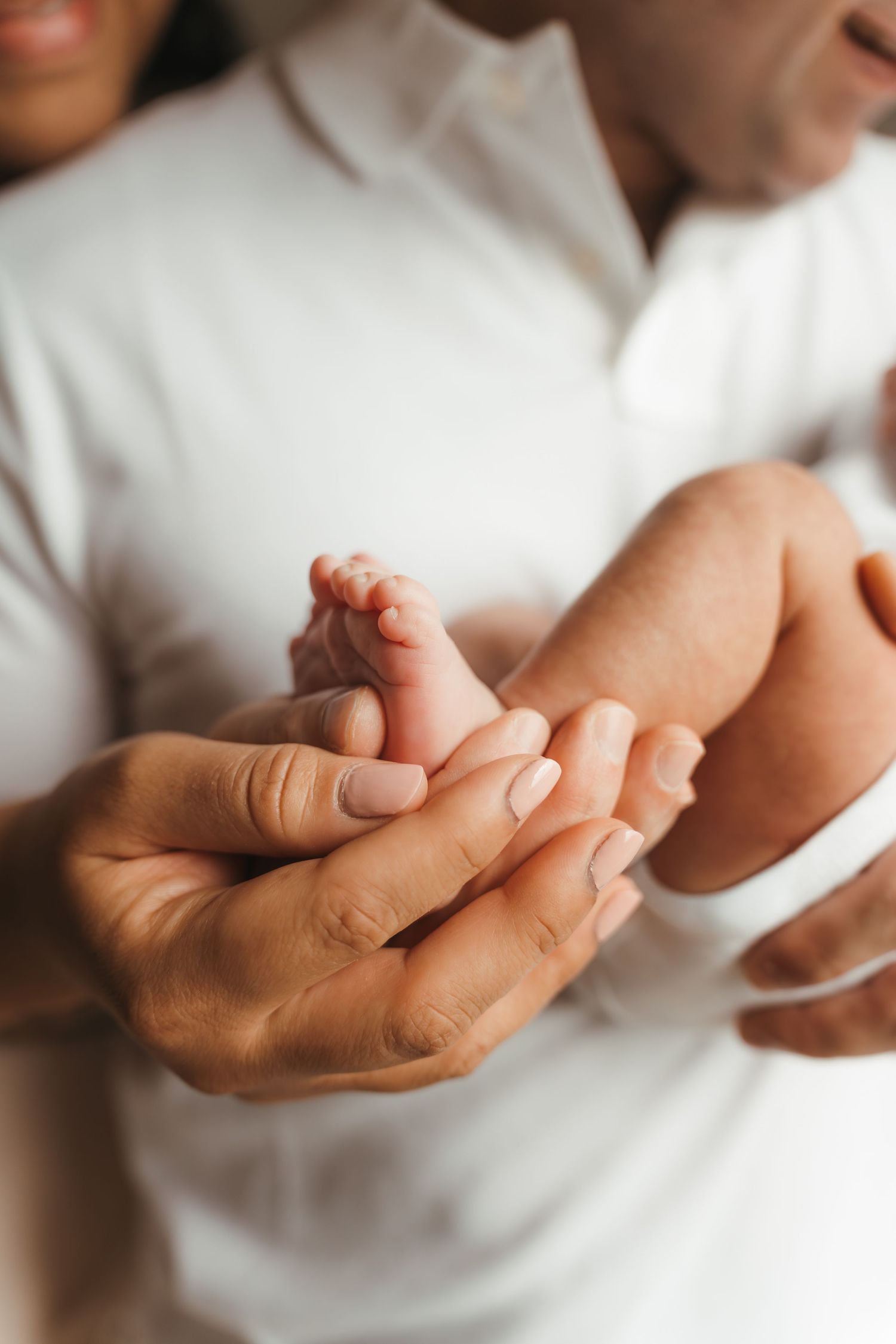Baby girls cradled in parents' arms during a Charlotte, NC lifestyle newborn session at home.