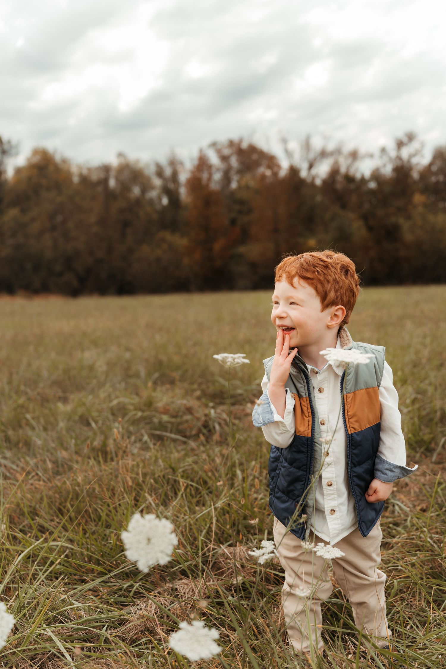 Little boy standing in an open field laughing during this lifestyle family session at Five Blossoms Farm located in Clover, SC
