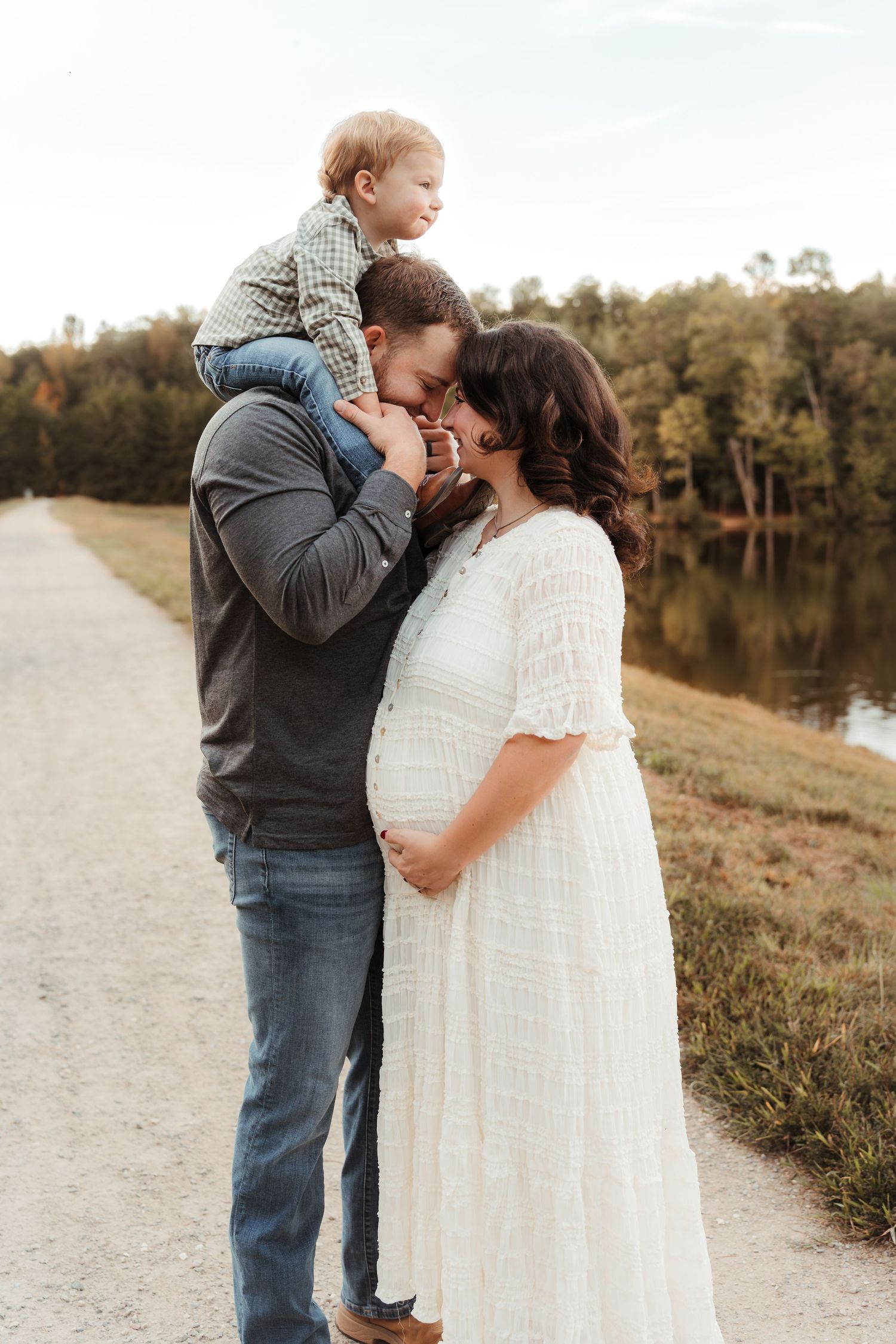 Family of three expecting another baby soon in soft natural light during an outdoor maternity session in Charlotte, NC.
