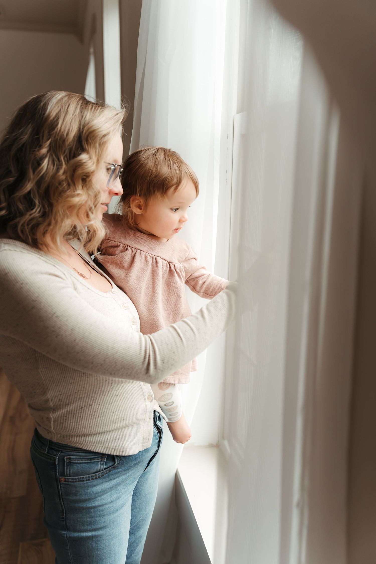 Mother and daughter looking out the window during this indoor family + milestone session near Charlotte, NC.