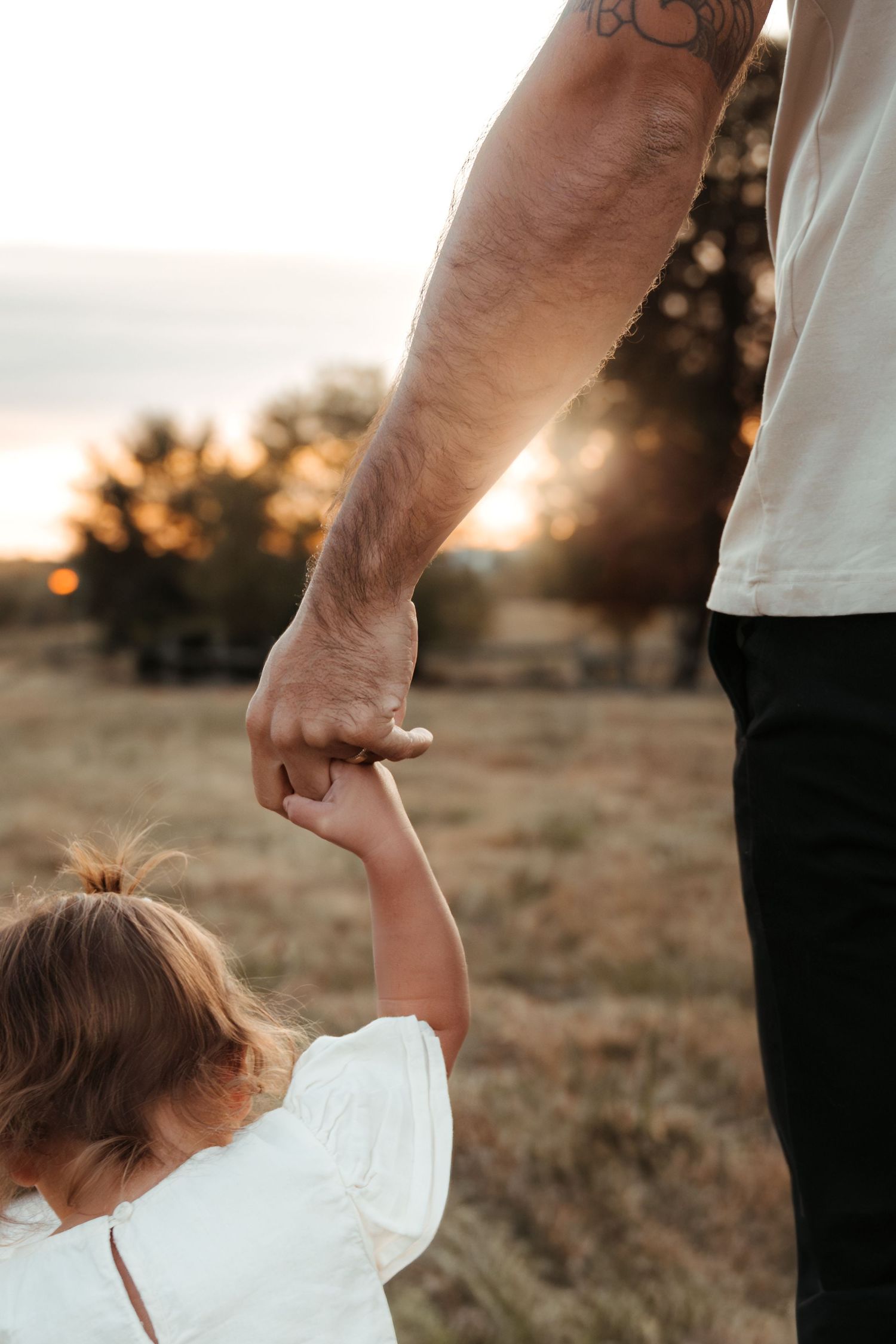 Little girl squeezing daddy's hand tightly during a golden hour family photo session in Fort Mill, SC.