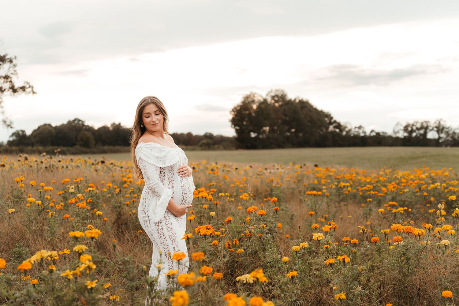 Mother holding belly in soft natural light during an outdoor maternity session near Charlotte, NC.