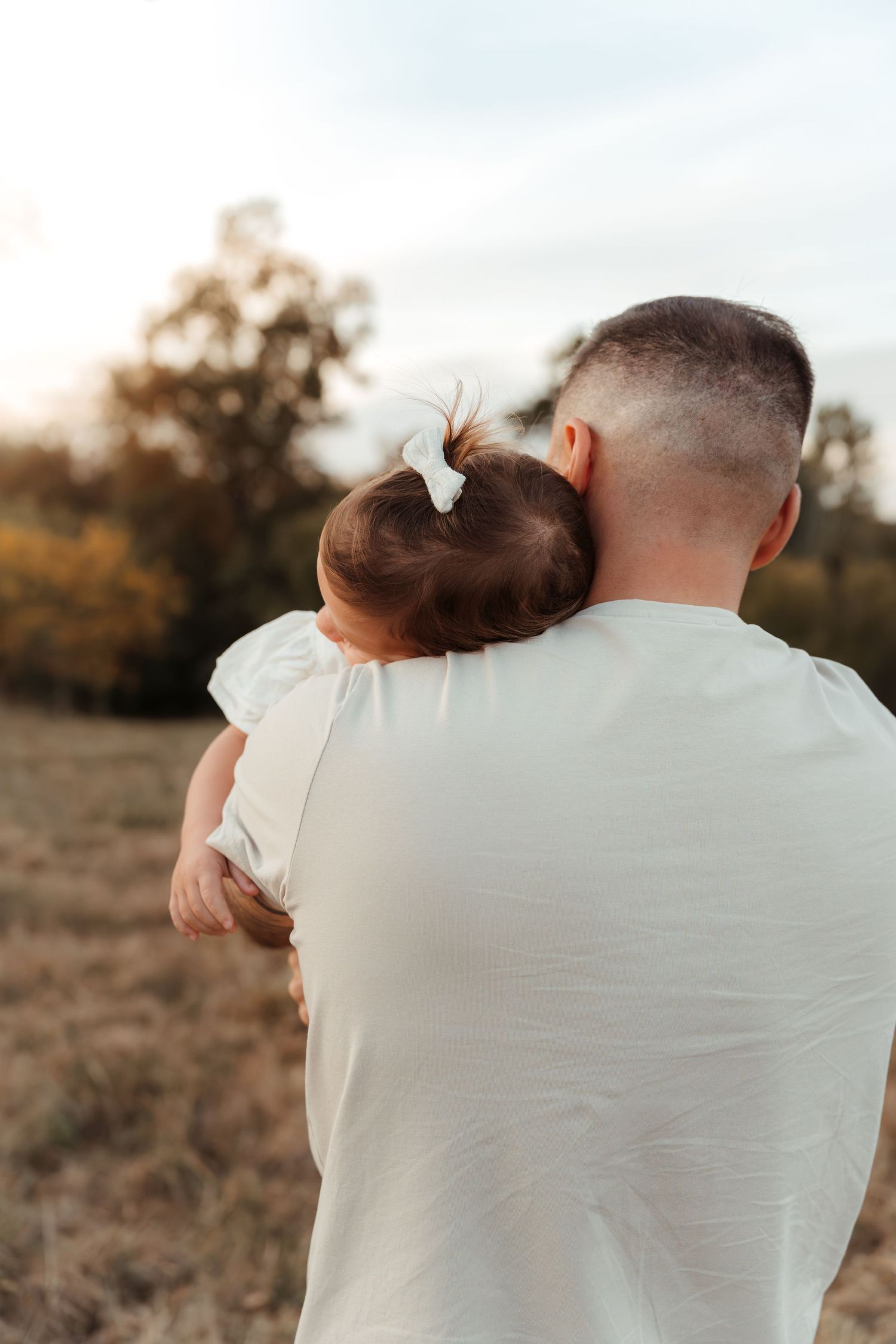 Little girl hugging her father tightly during a golden hour family photo session in Fort Mill, SC.
