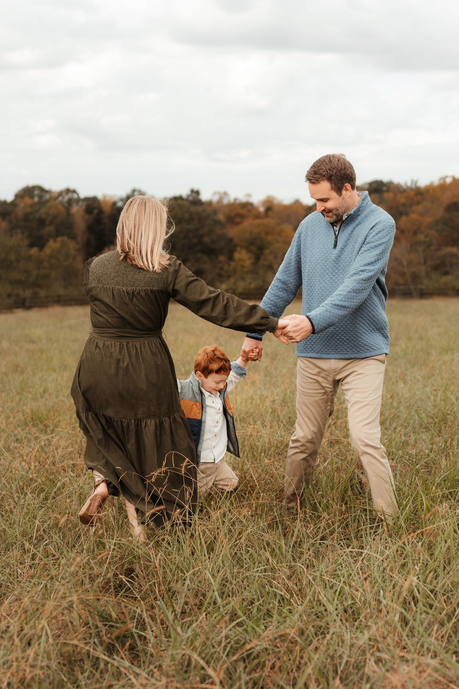Family of three playing ring-around-the-rosie during this lifestyle family session at Five Blossoms Farm located in Clover, SC
