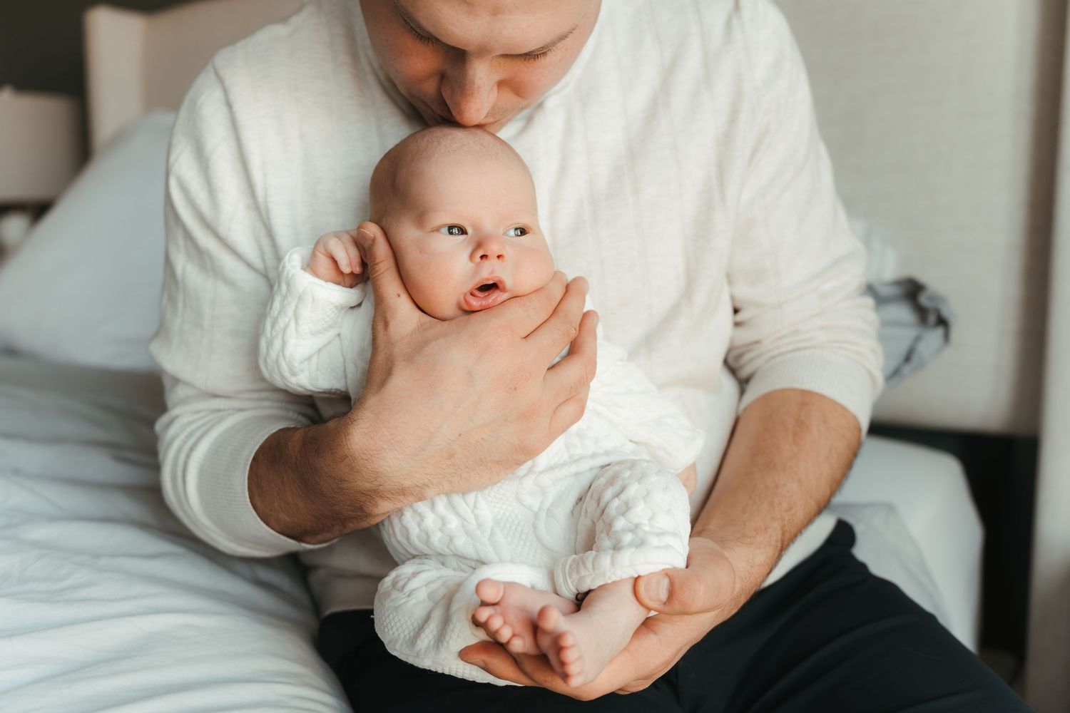 Newborn wrapped against father's chest, capturing early connection in a Charlotte, NC in-home lifestyle session.