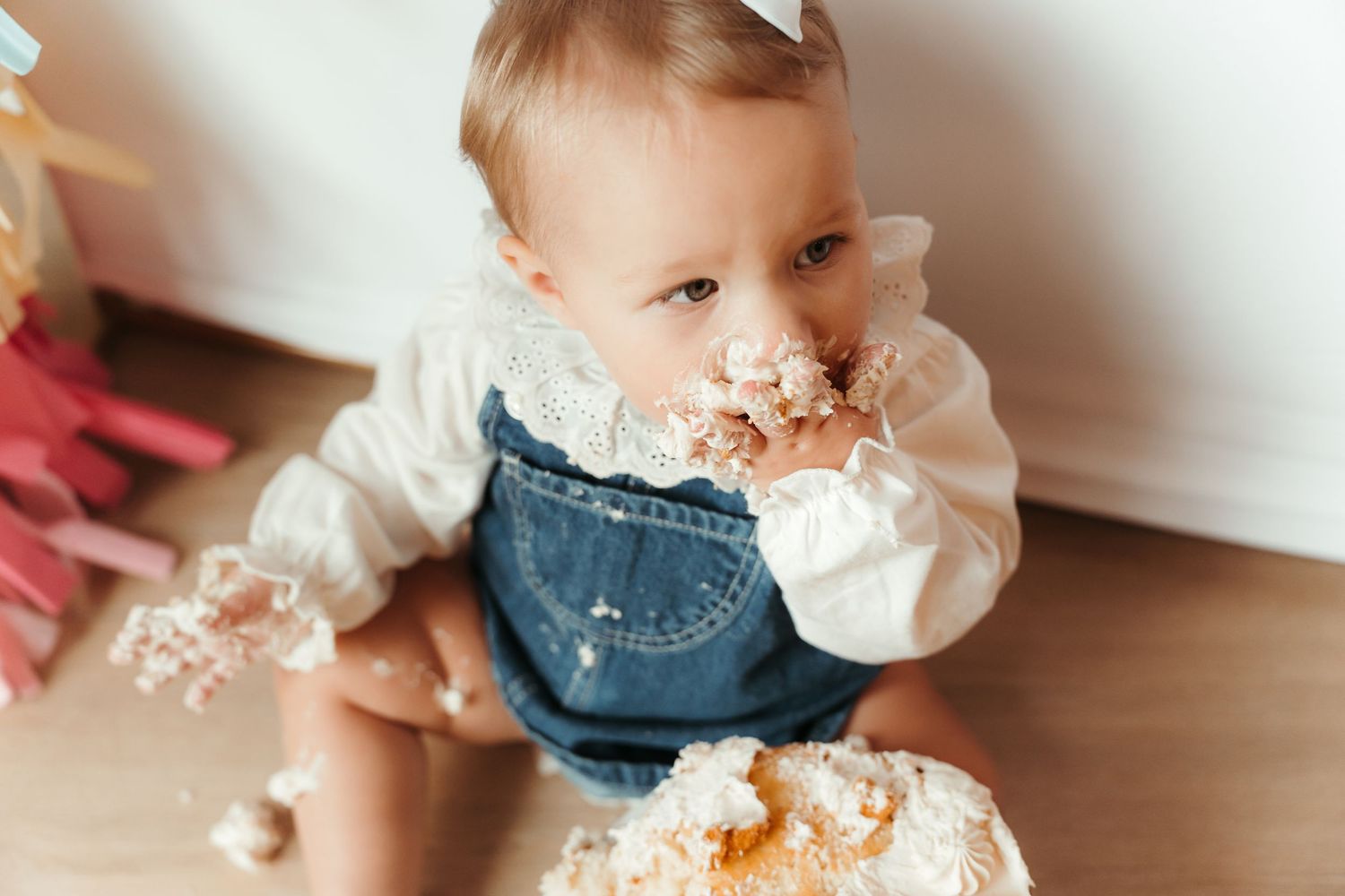 Baby girl reaching for her first birthday cake during an in-home milestone session in Charlotte, NC.