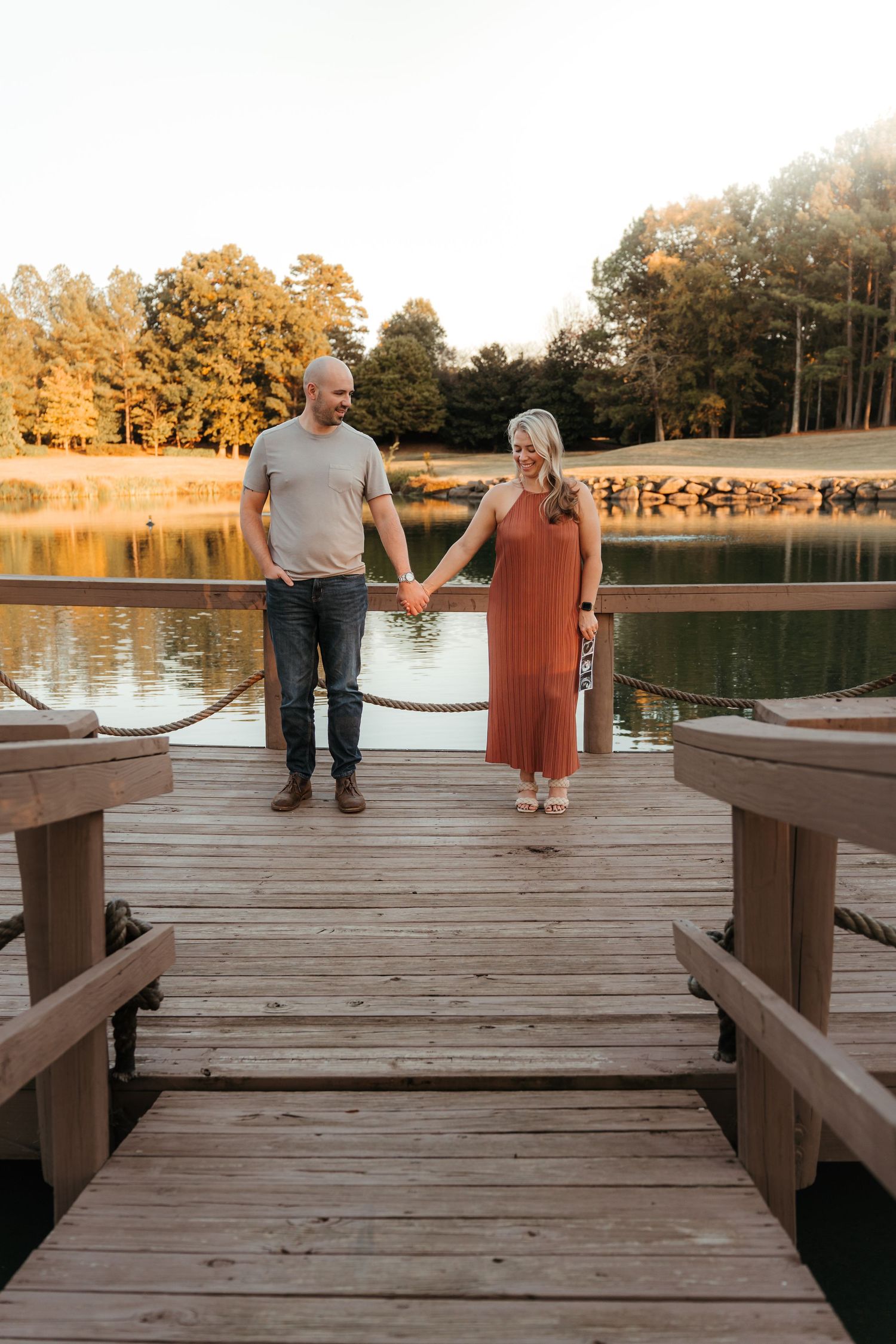 Expecting couple walking hand-in-hand through a Charlotte, NC park during a lifestyle maternity session.