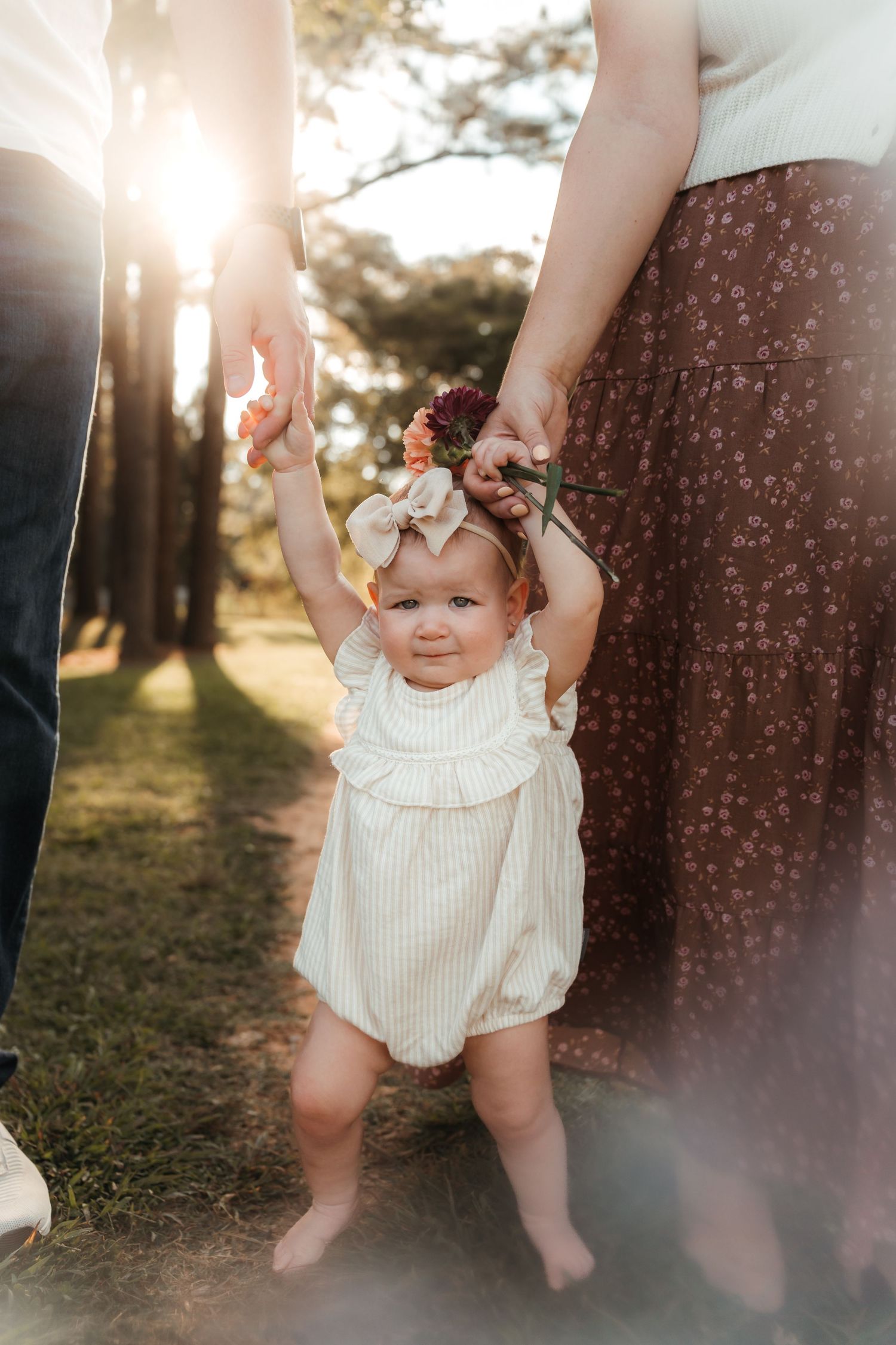 Baby girl reaching for her mom and dad's hands during an outdoor milestone session in Charlotte, NC.