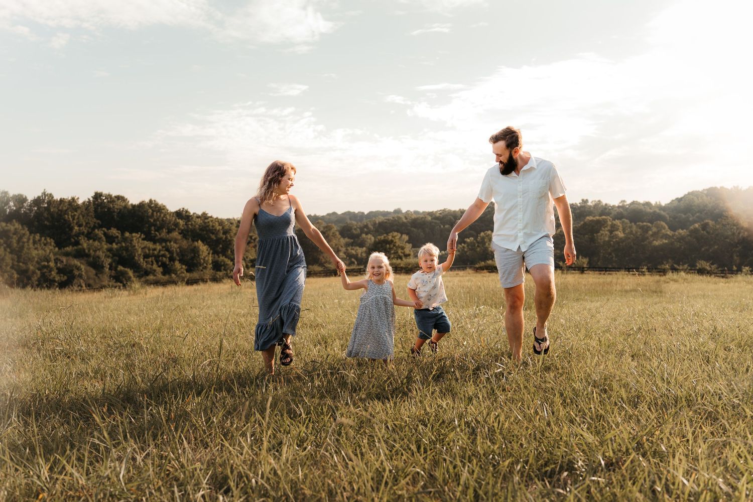 Family walking hand-in-hand in an open field at Five Blossoms Farm in Clover, SC during lifestyle photography.
