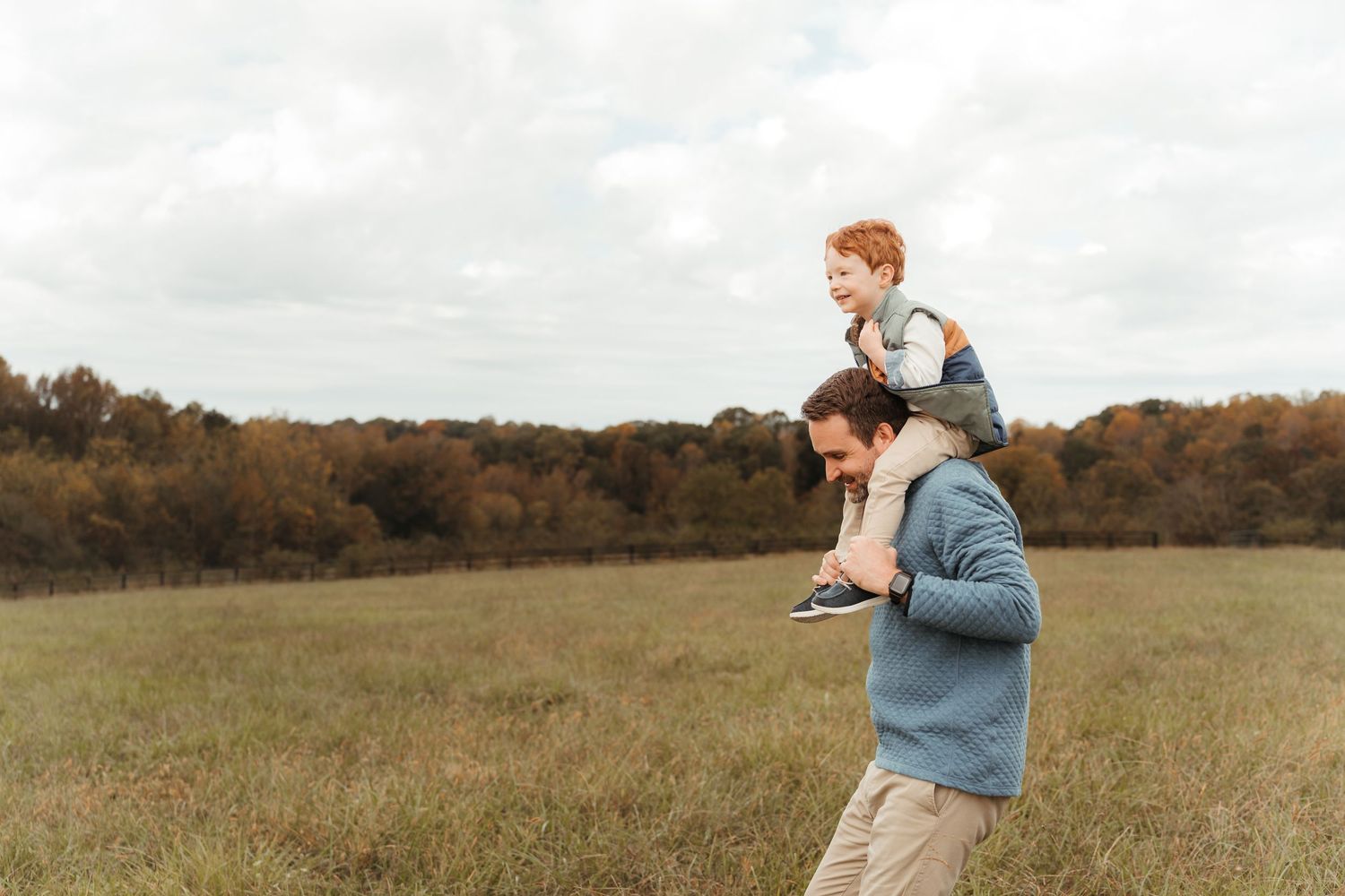 Dad running through an open field with his son during this lifestyle family session at Five Blossoms Farm located in Clover, SC