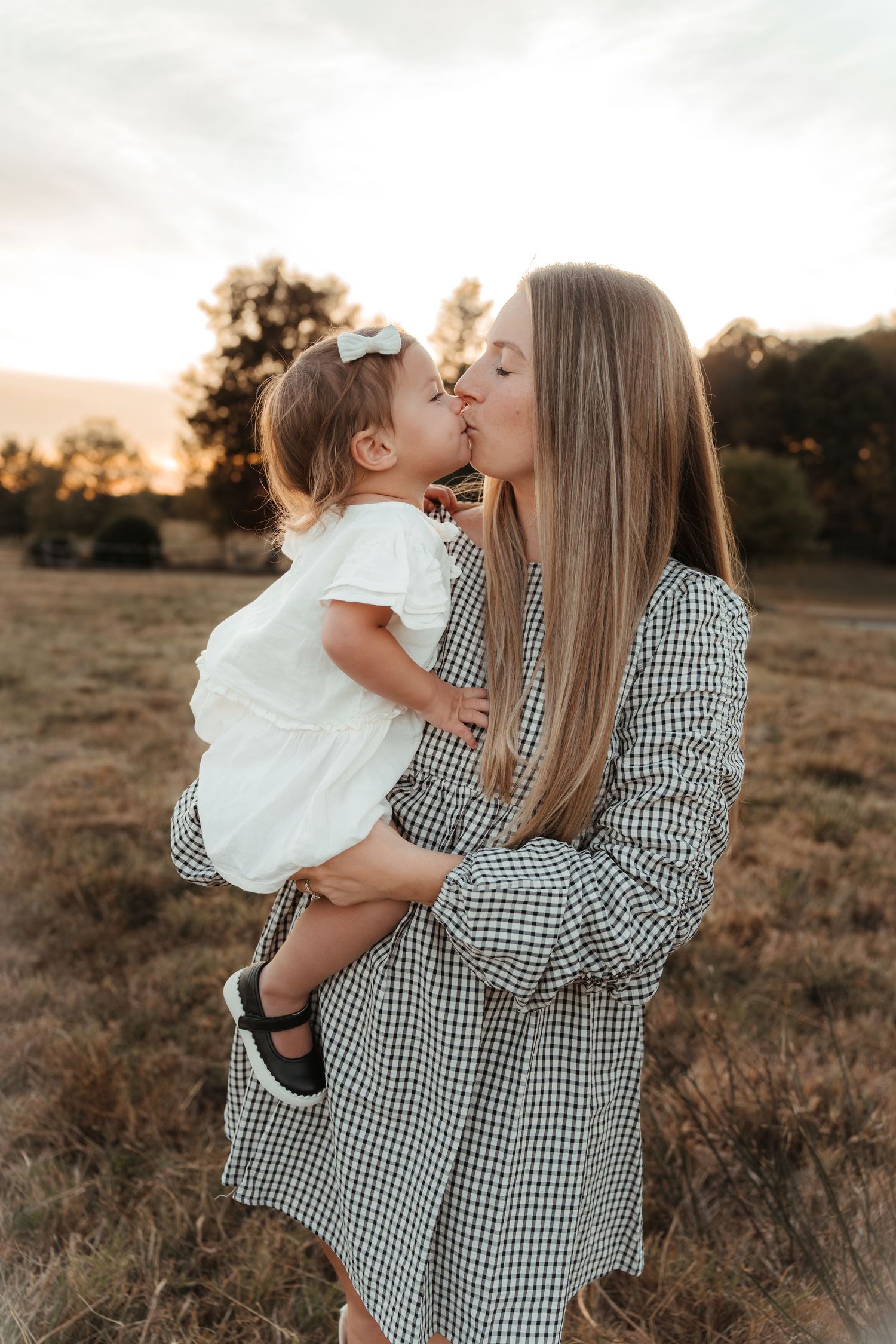 Little girl kissing her mother during a golden hour family photo session in Fort Mill, SC.